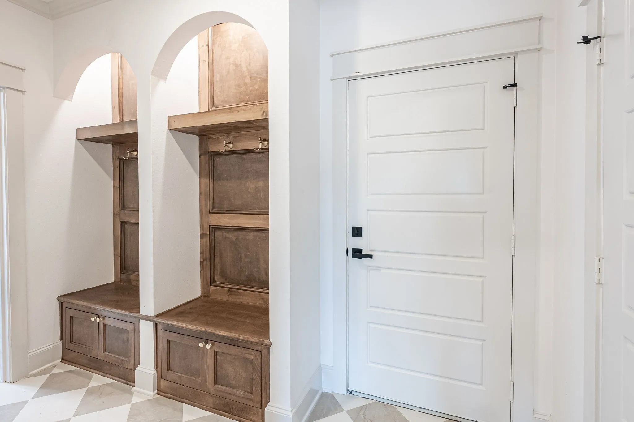 Built-in wooden bench with storage, arched alcoves, and decorative wall hooks