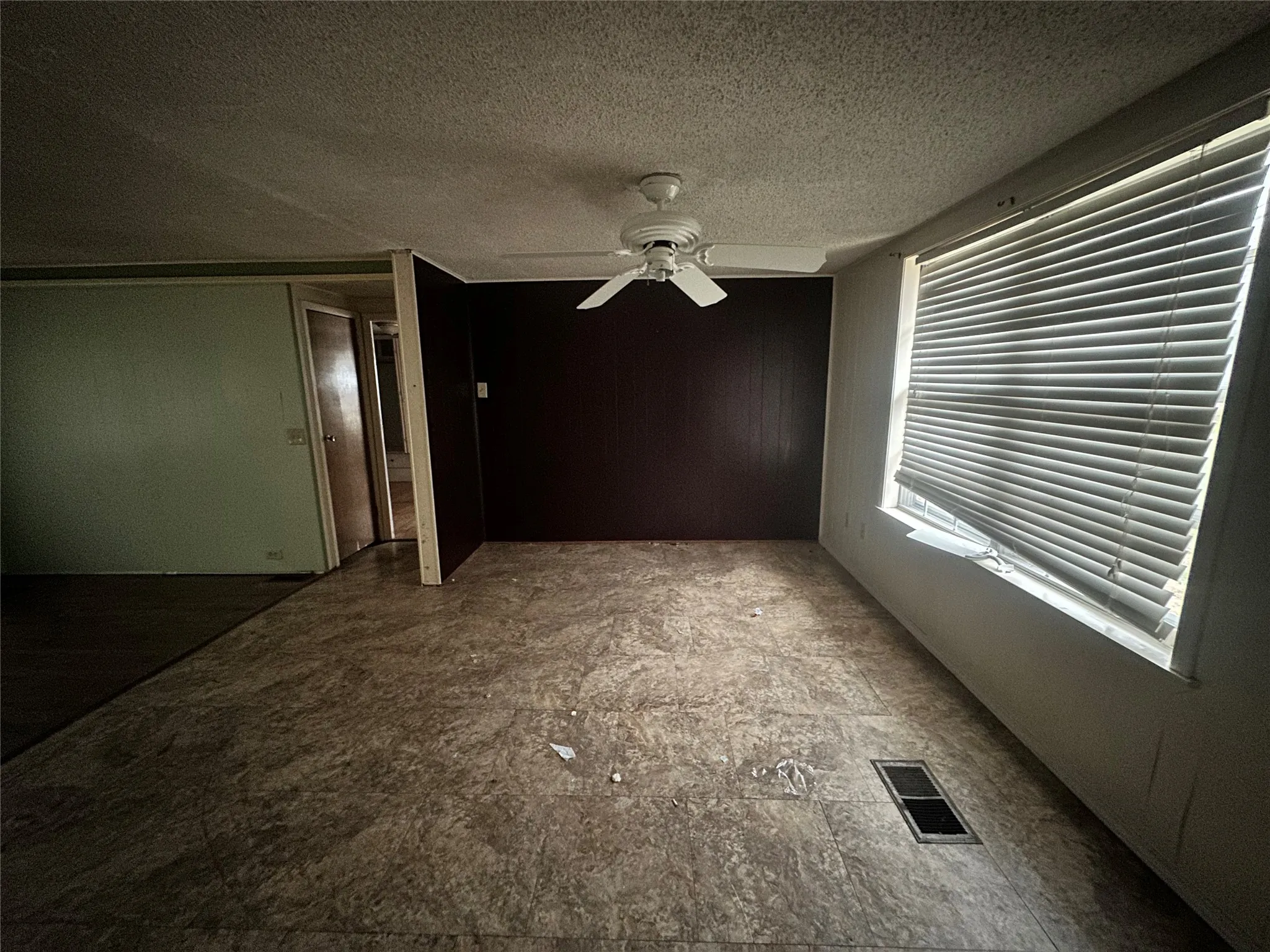Empty room featuring ceiling fan and a textured ceiling