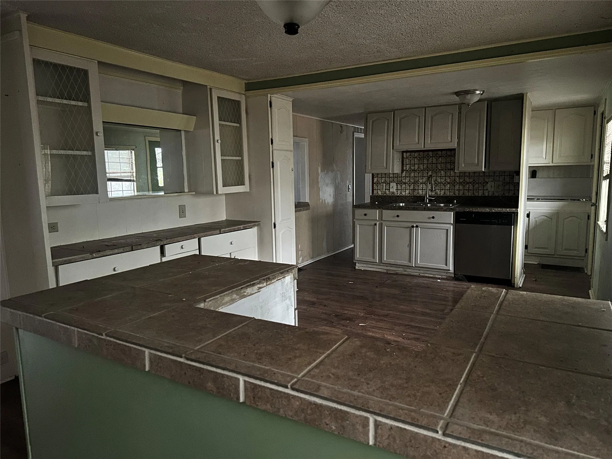Kitchen with tasteful backsplash, sink, dishwasher, a textured ceiling, and kitchen peninsula
