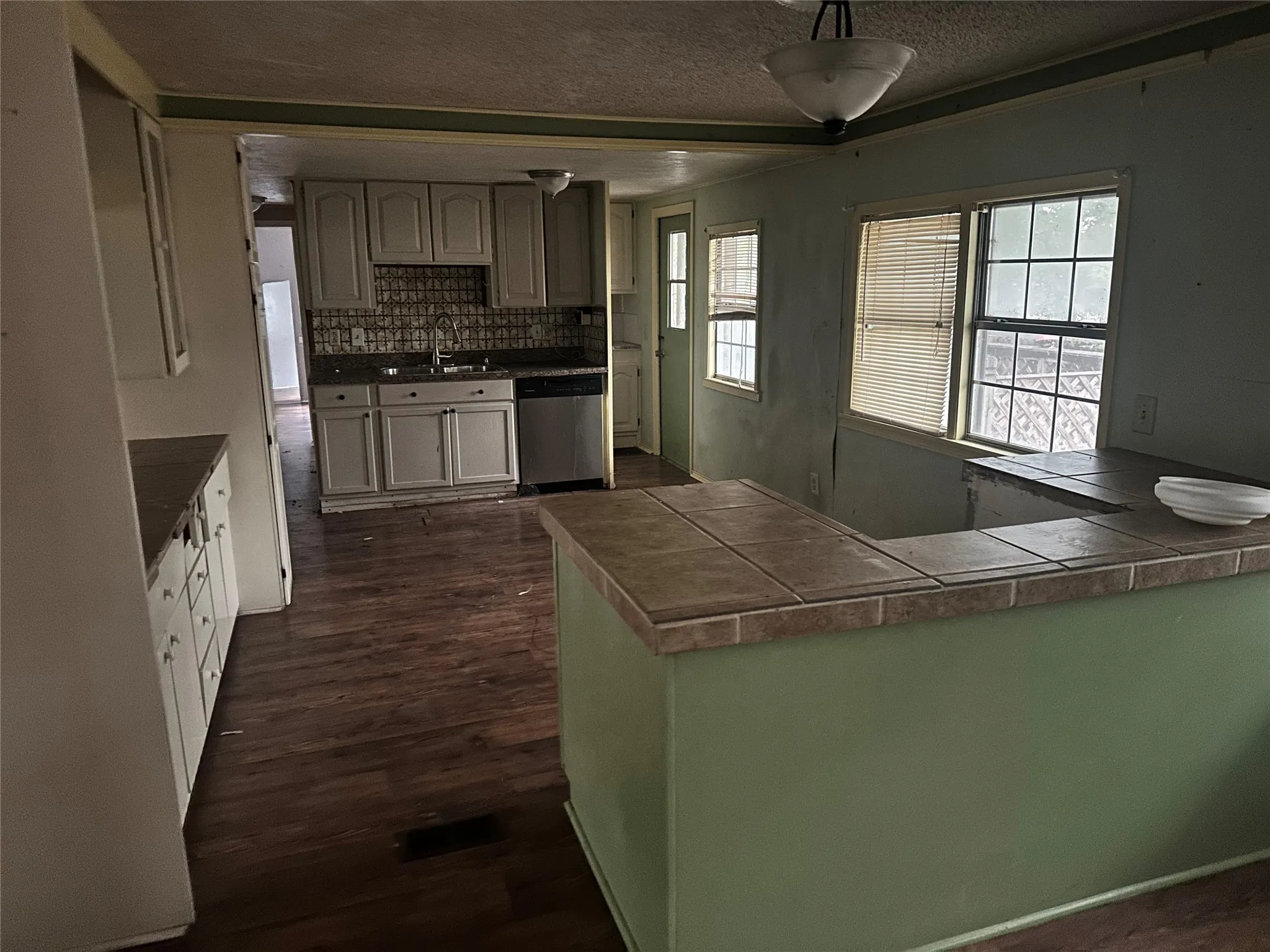 Kitchen featuring kitchen peninsula, stainless steel dishwasher, sink, and backsplash
