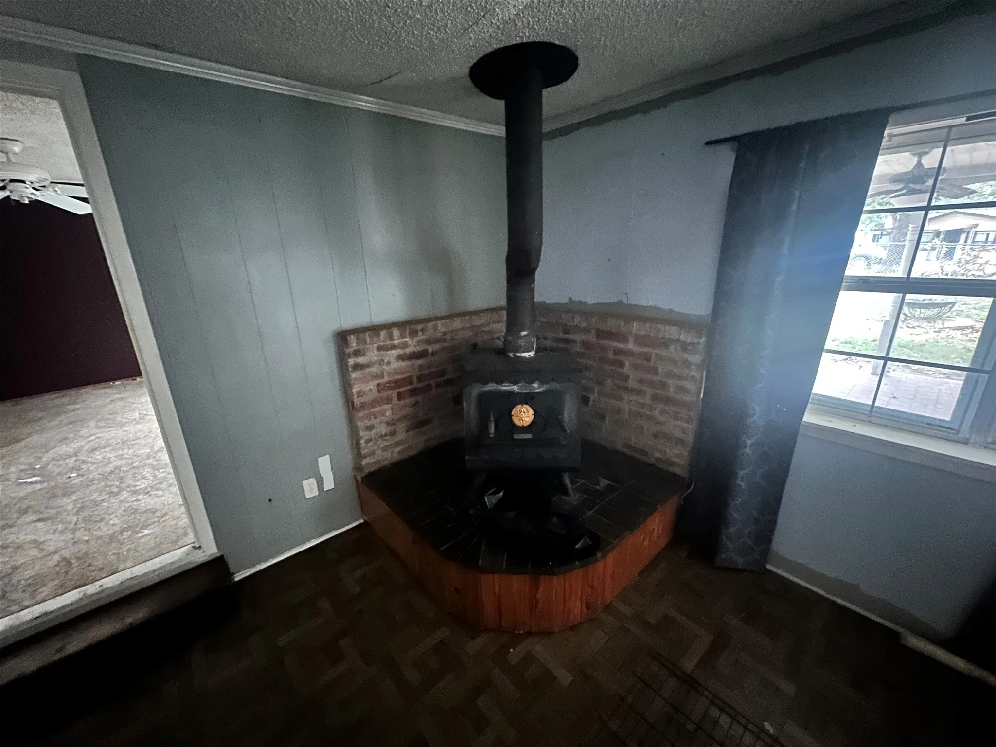 Room details with a wood stove, parquet floors, a textured ceiling, and crown molding