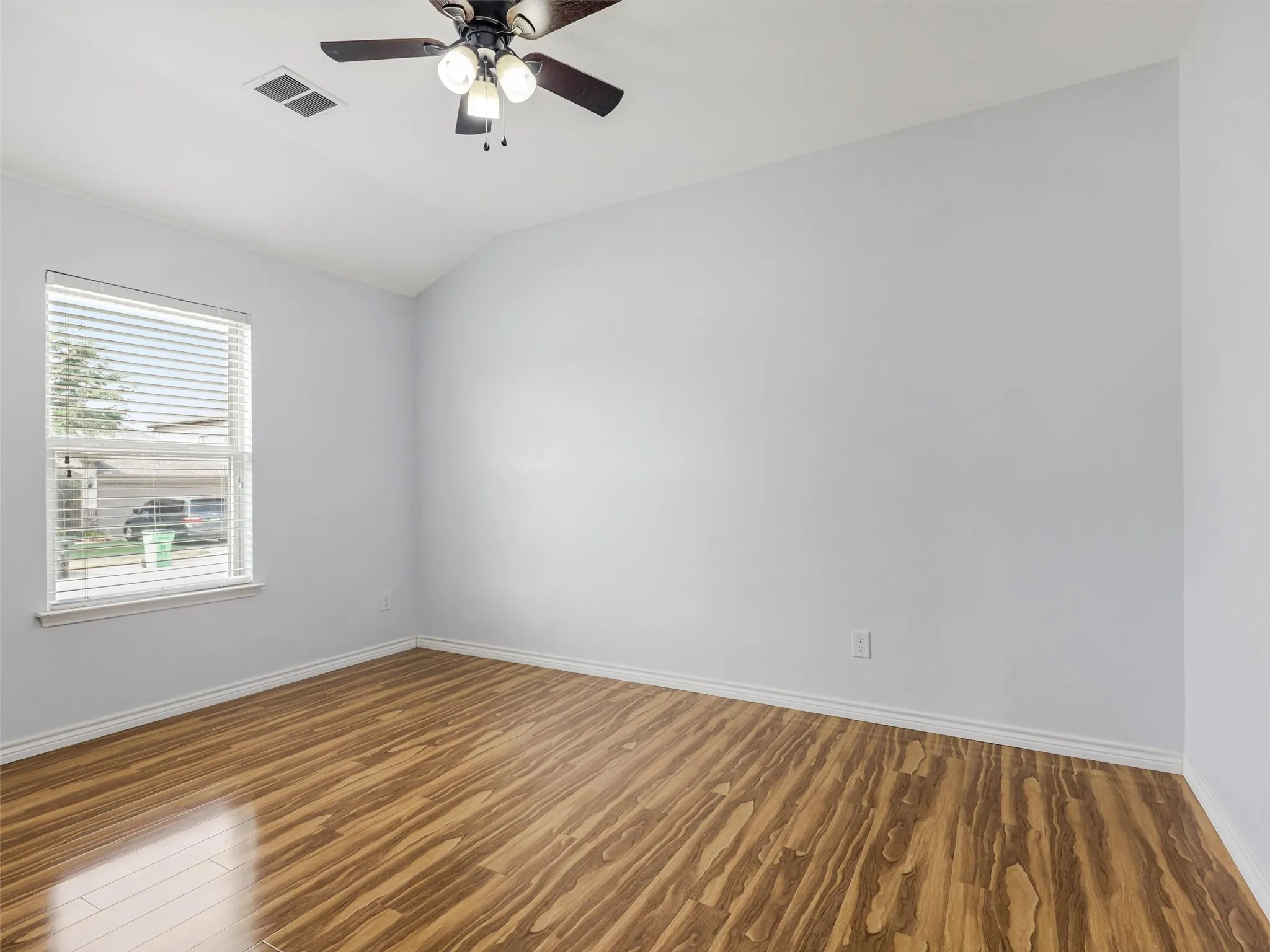 Room featuring wood-finish flooring, white baseboards, and light gray walls