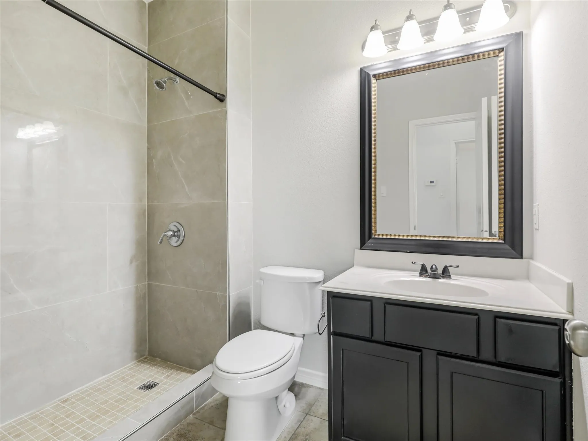 Bathroom featuring a walk-in shower with large format tile walls and a tiled shower pan