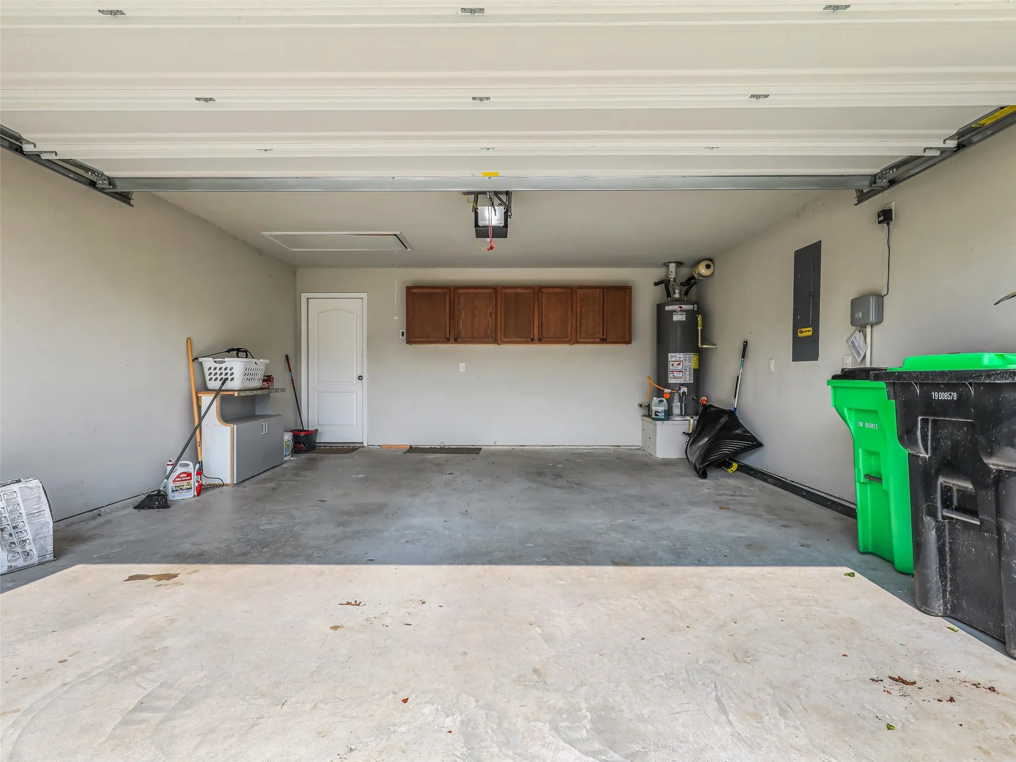 Spacious two-car garage with overhead storage, a dedicated utility closet, and built-in wood-finish cabinetry
