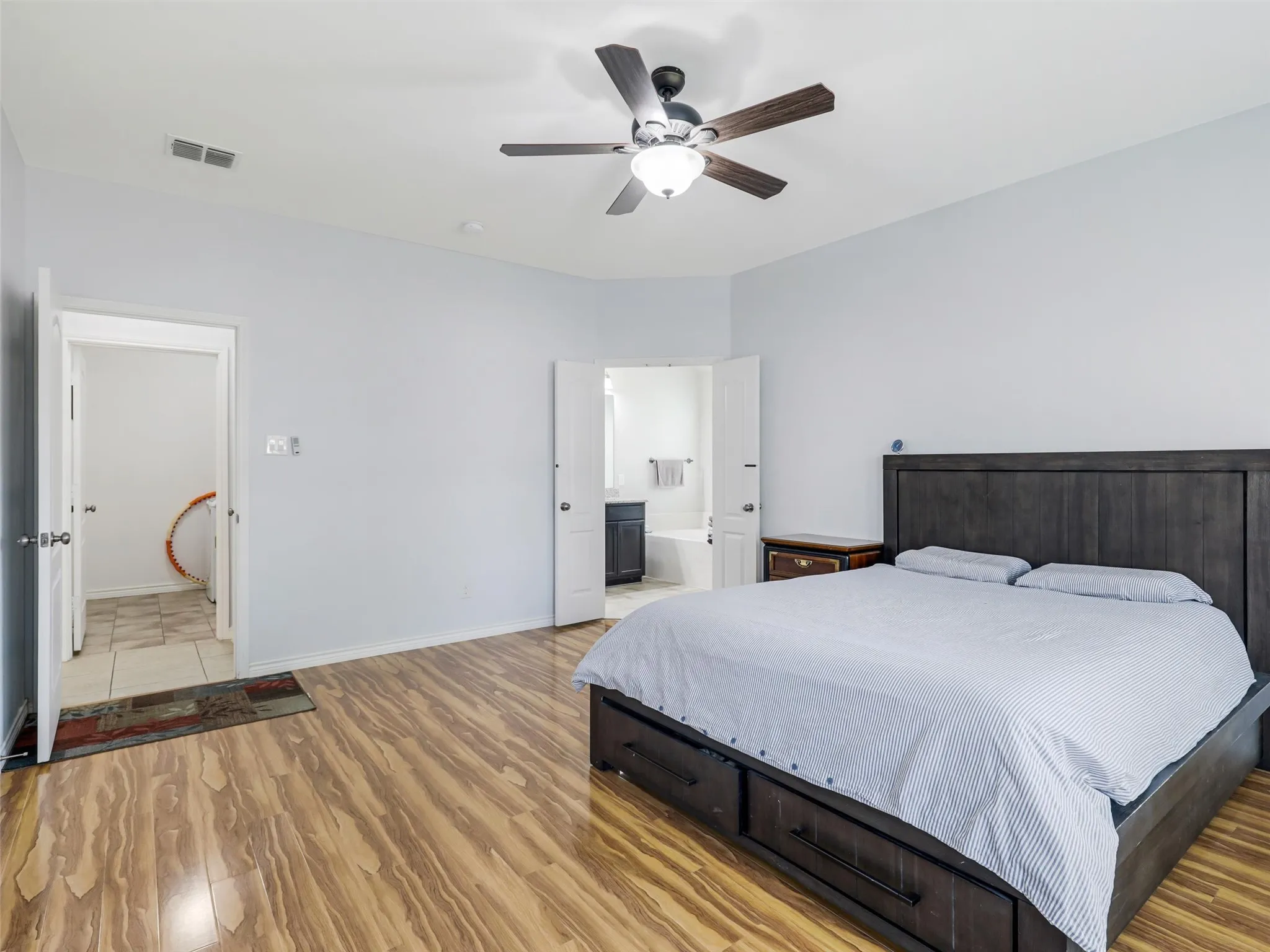 Spacious room featuring wood-finish flooring, a contemporary ceiling fan with integrated lighting, and light-toned wall paint
