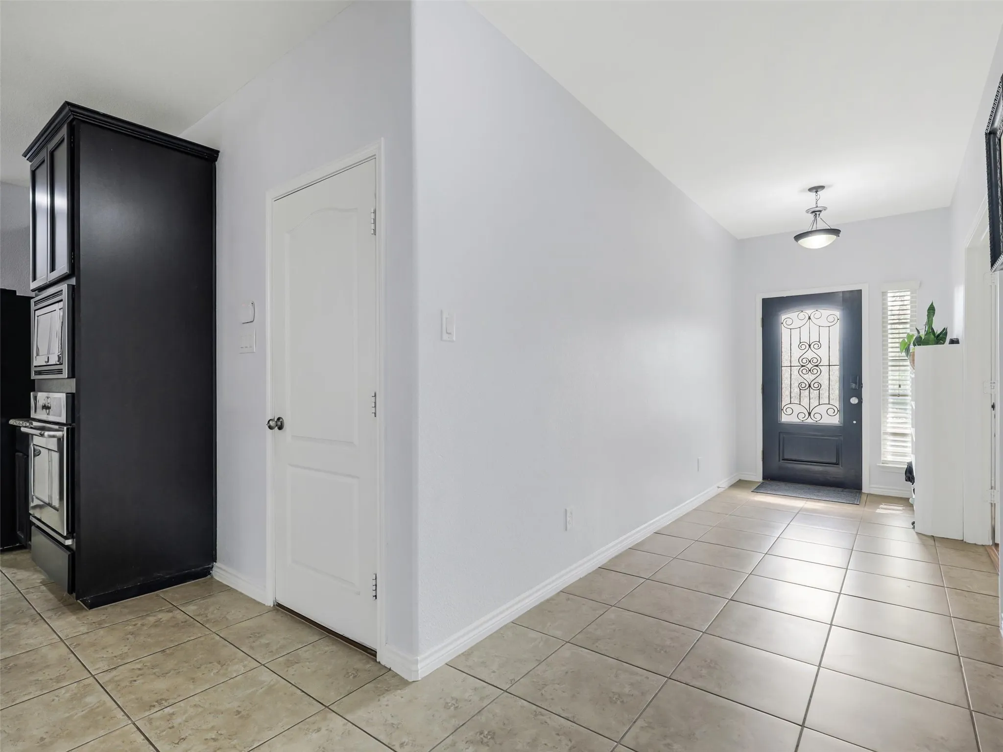 Entryway featuring a dark paneled door with decorative glass, tiled flooring, and a semi-flush mount ceiling light