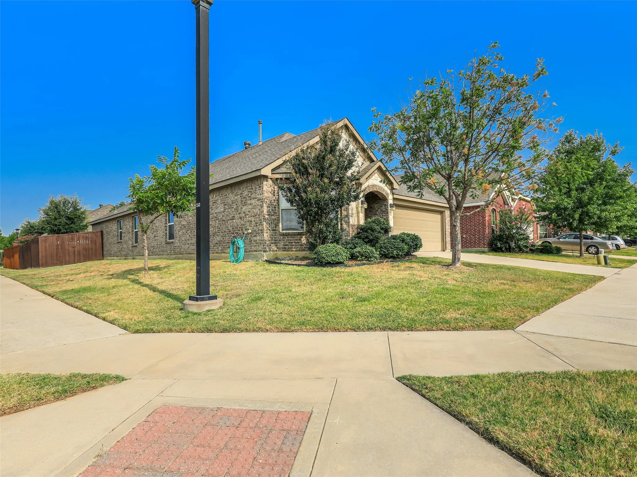Brick exterior with an arched entry, attached garage, and established landscaping