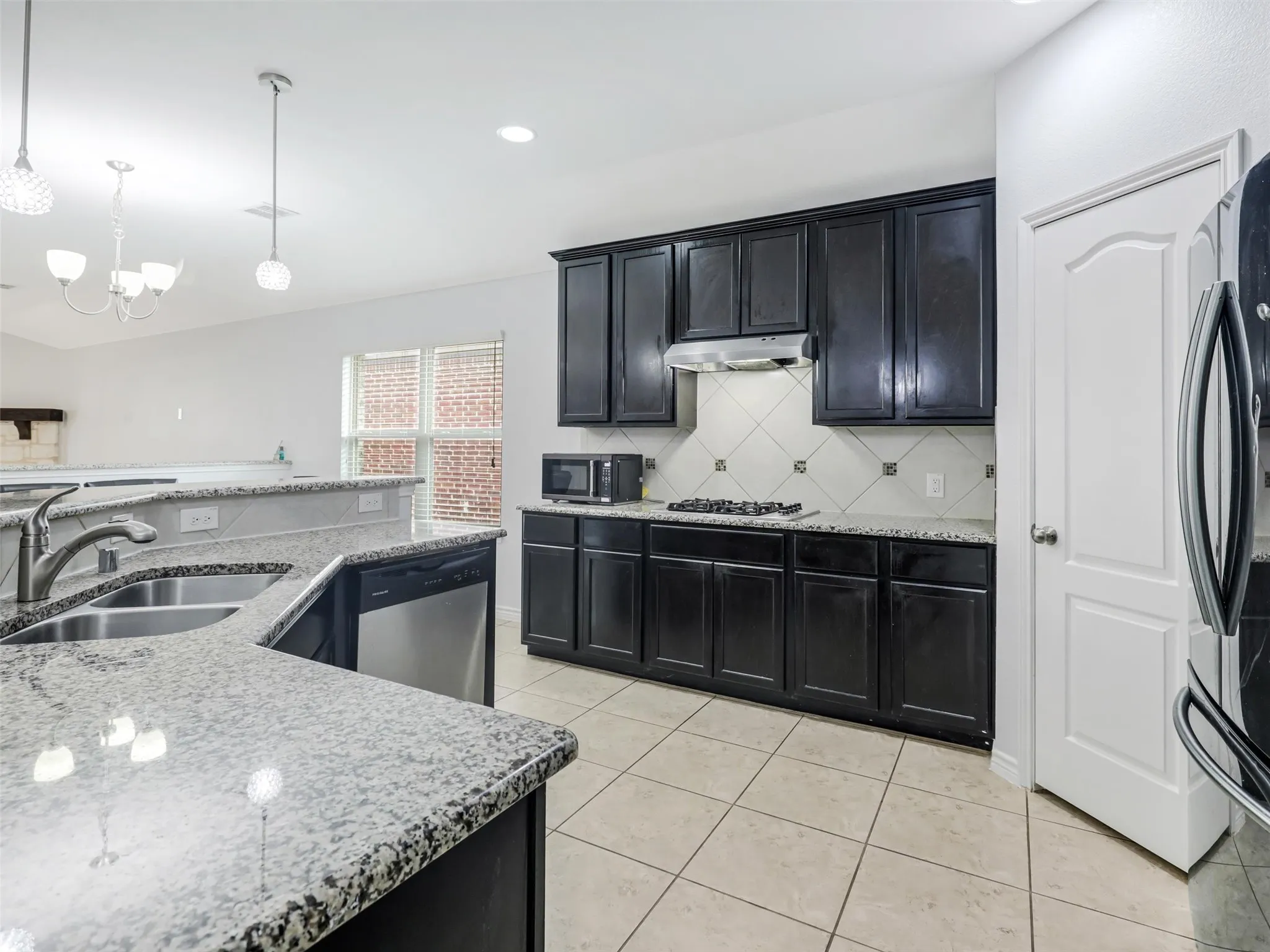 Kitchen featuring dark cabinetry, speckled countertops, stainless steel appliances, and tile flooring