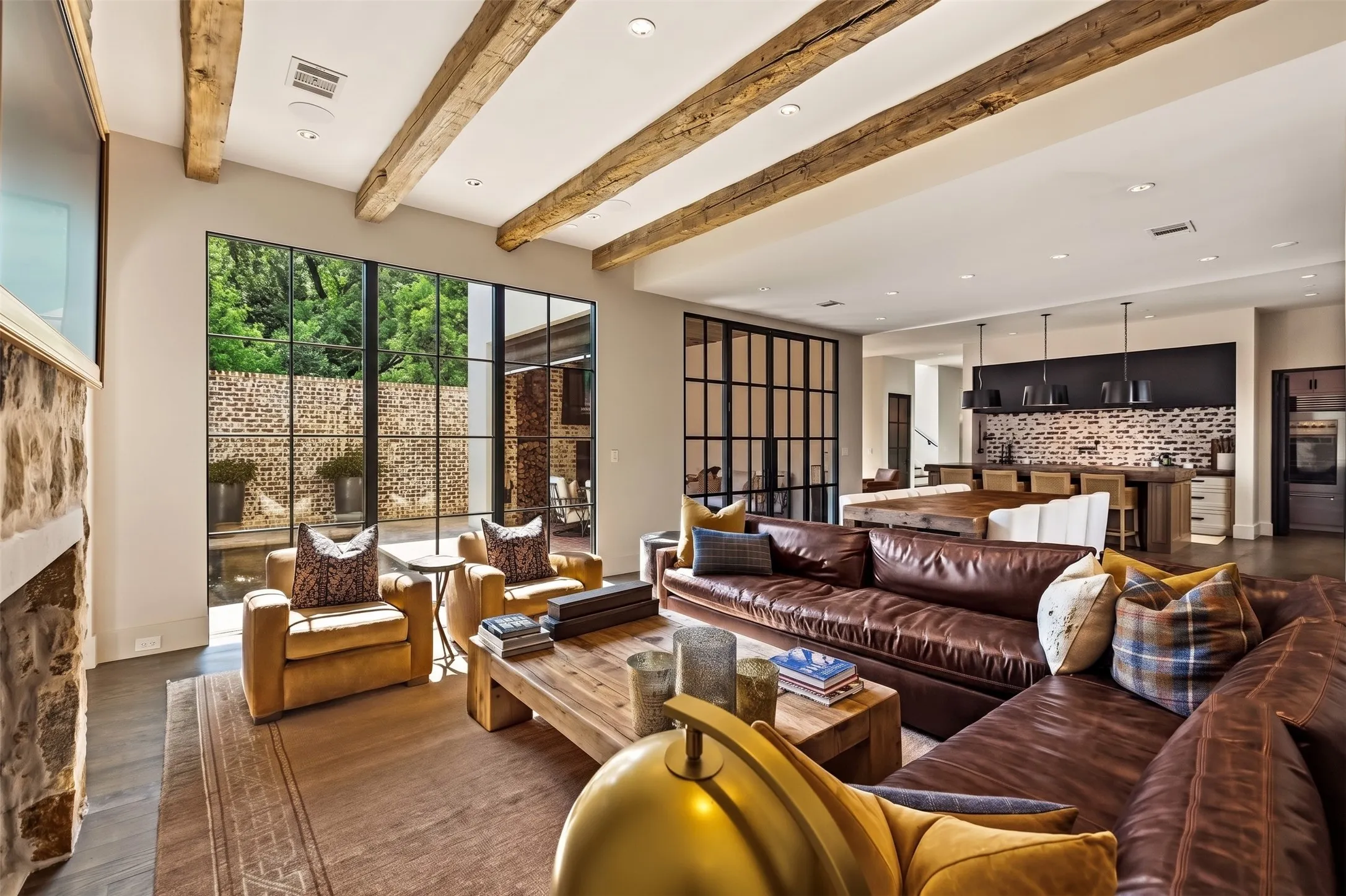 Exposed wood ceiling beams, recessed lighting, expansive multi-pane windows, stone-clad fireplace, and wood-finish flooring