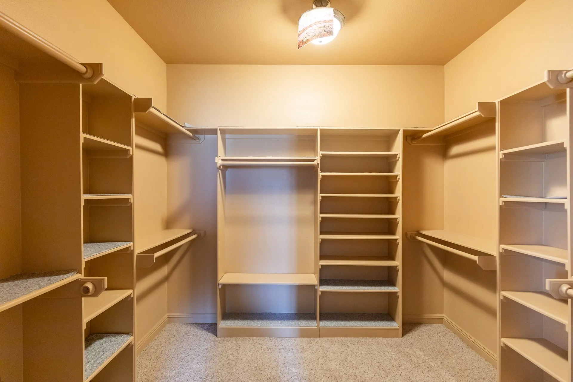 Walk-in closet featuring extensive built-in shelving, multiple hanging rods, and light-colored carpeting