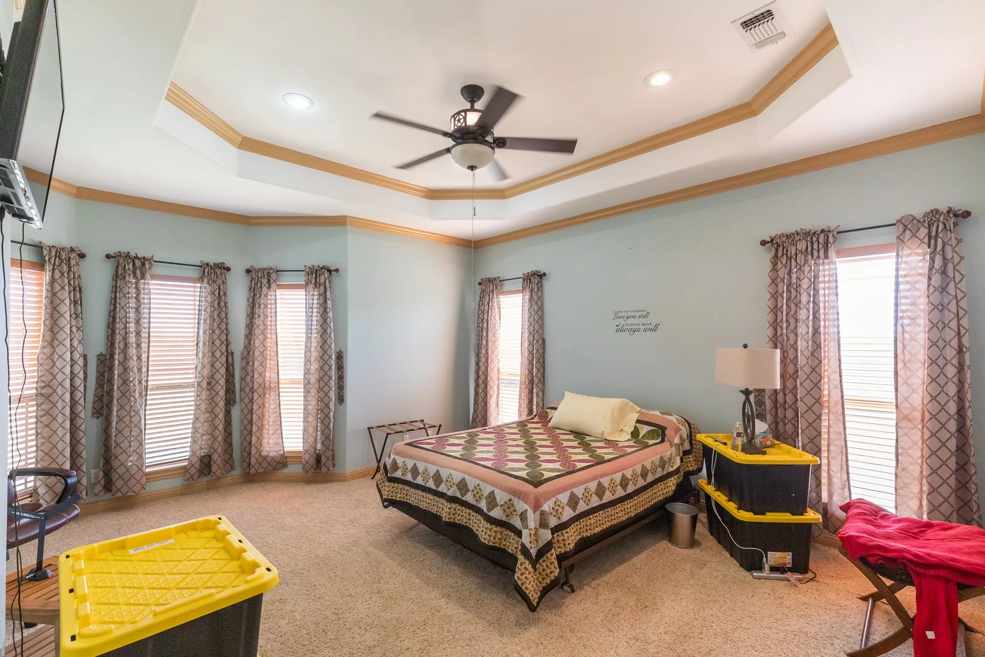 Spacious room featuring a tiered tray ceiling with recessed lighting and a ceiling fan
