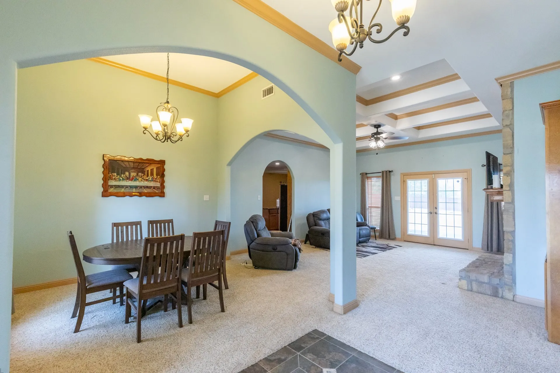 Open concept living area with arched entryways, a tray ceiling, and French doors