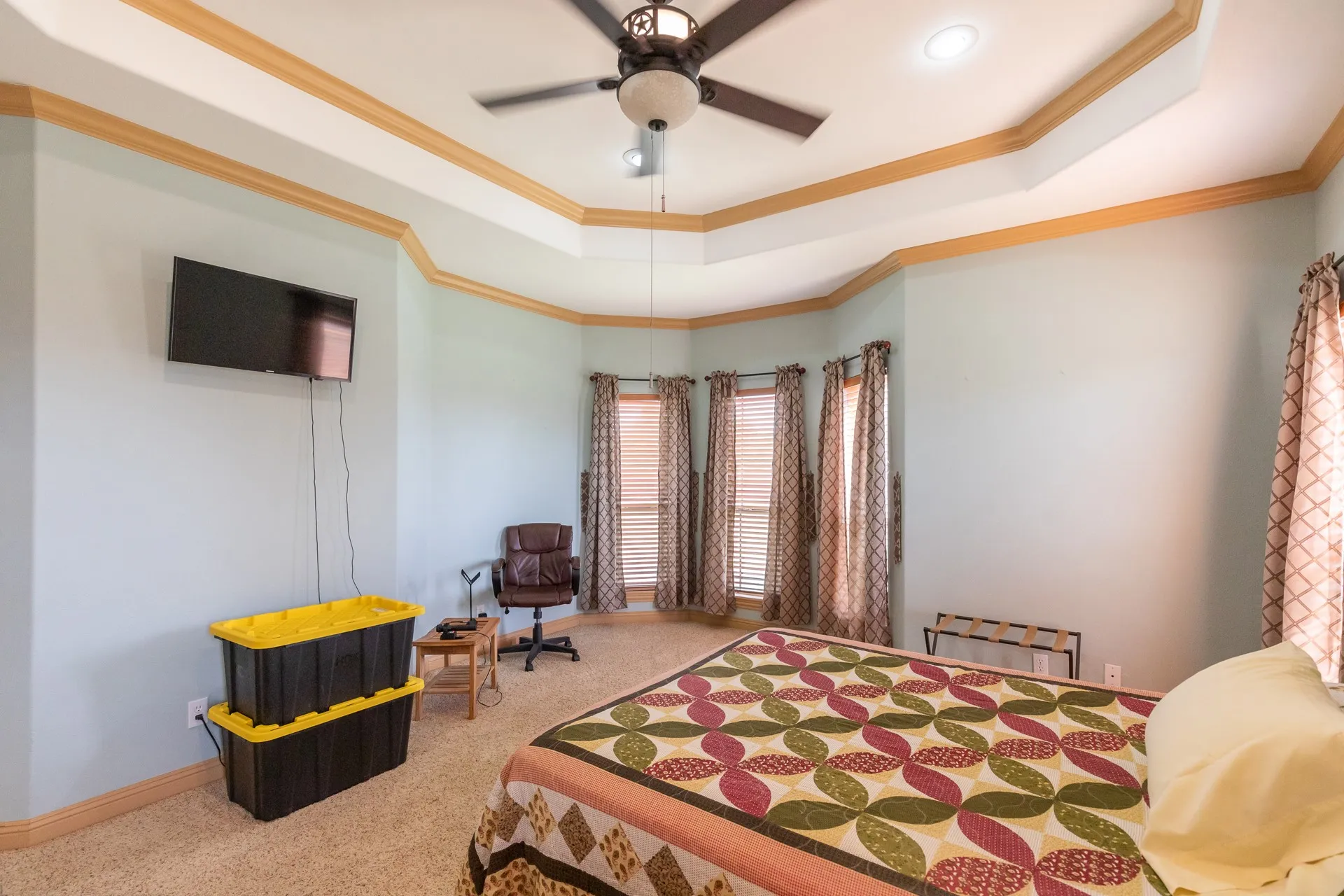 Carpeted room featuring a tray ceiling with wood trim, recessed lighting, and a ceiling fan