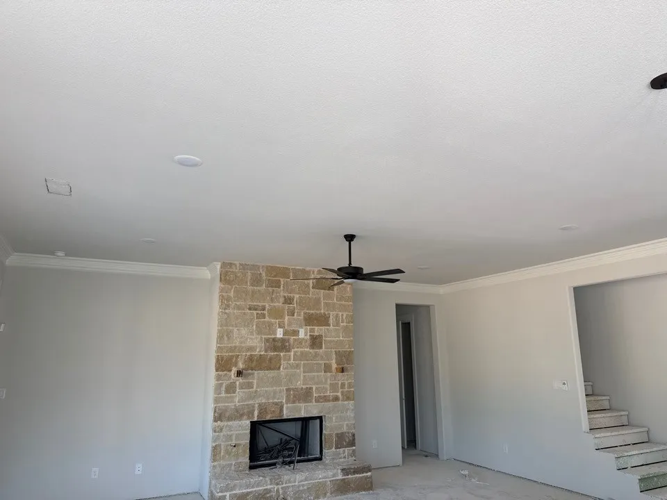 Stacked stone fireplace with a black firebox, crown molding, a ceiling fan, and recessed lighting