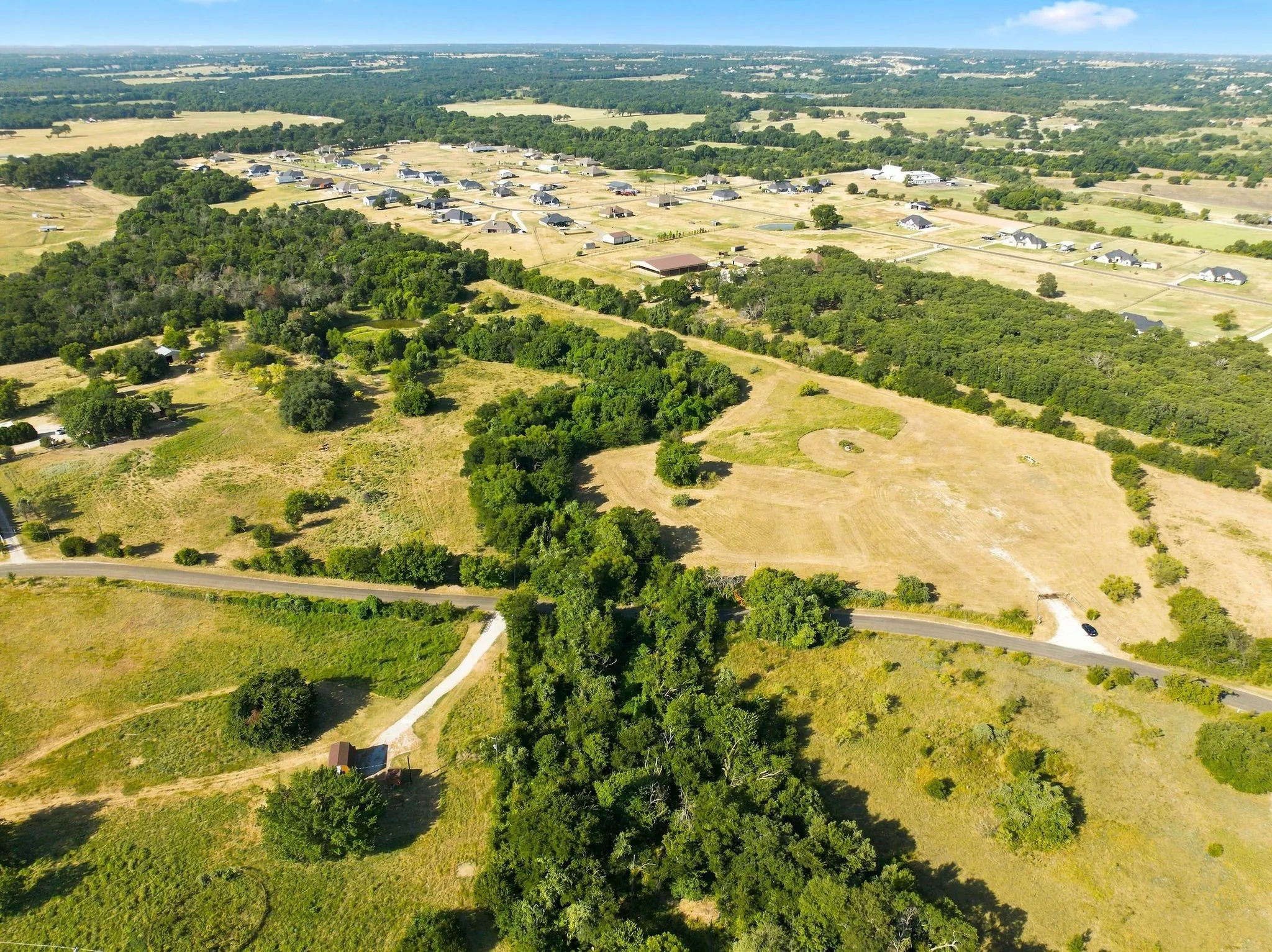 Sprawling rural acreage featuring mature tree lines, open pastureland, and established property boundaries