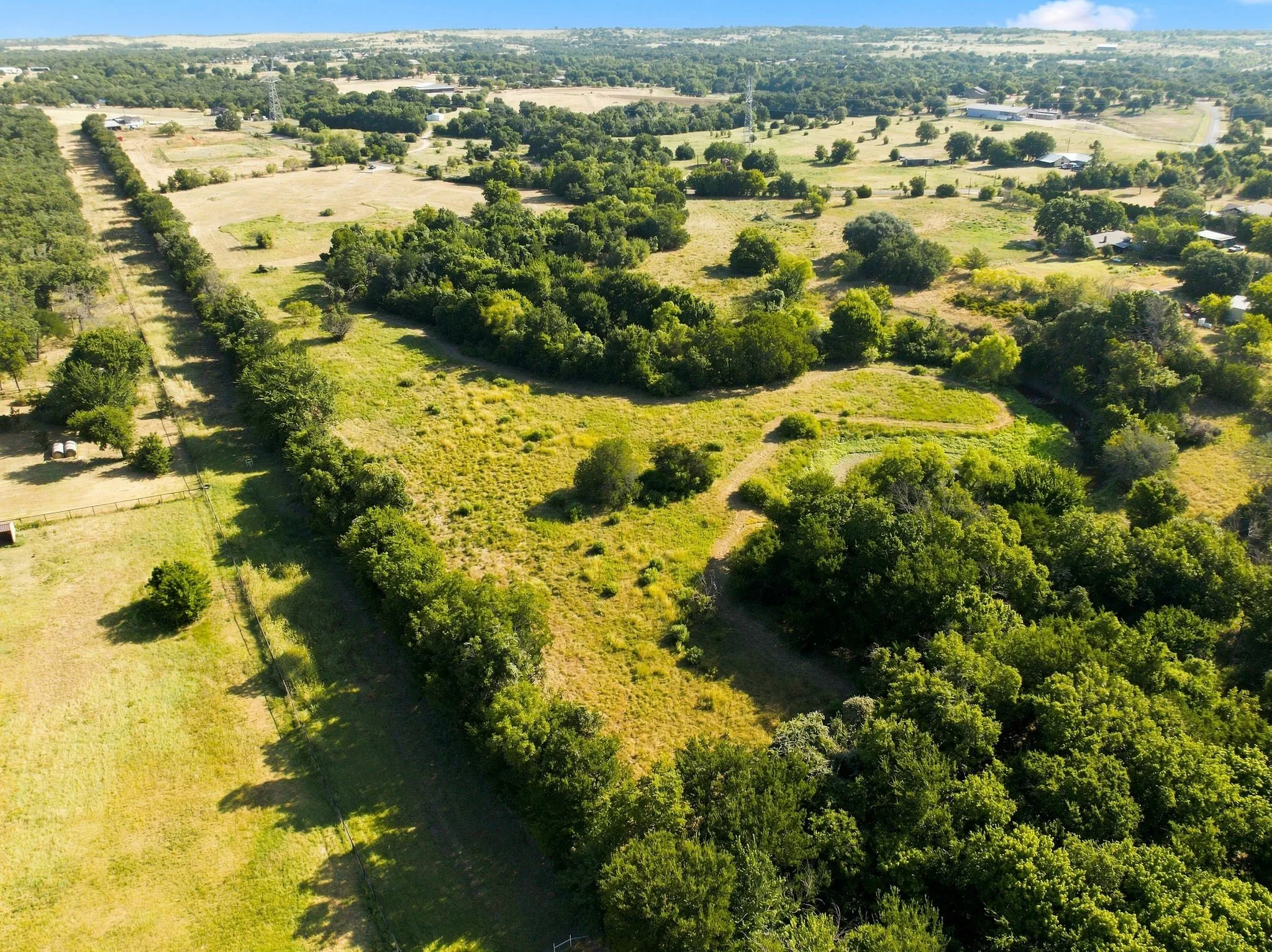 Sprawling rural acreage featuring mature tree clusters, open pastureland, and established tree-lined perimeter