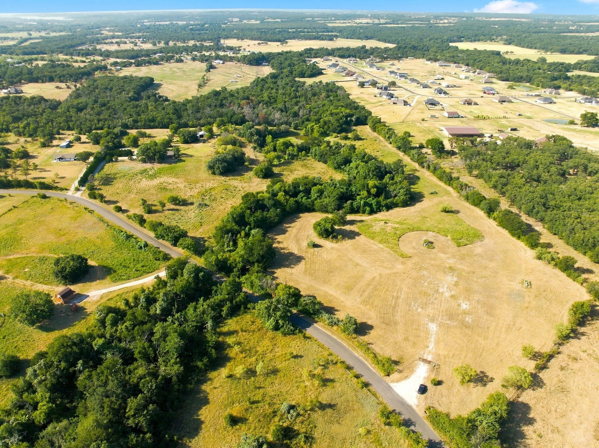 Expansive rural landscape featuring scattered trees, open fields, and paved roads