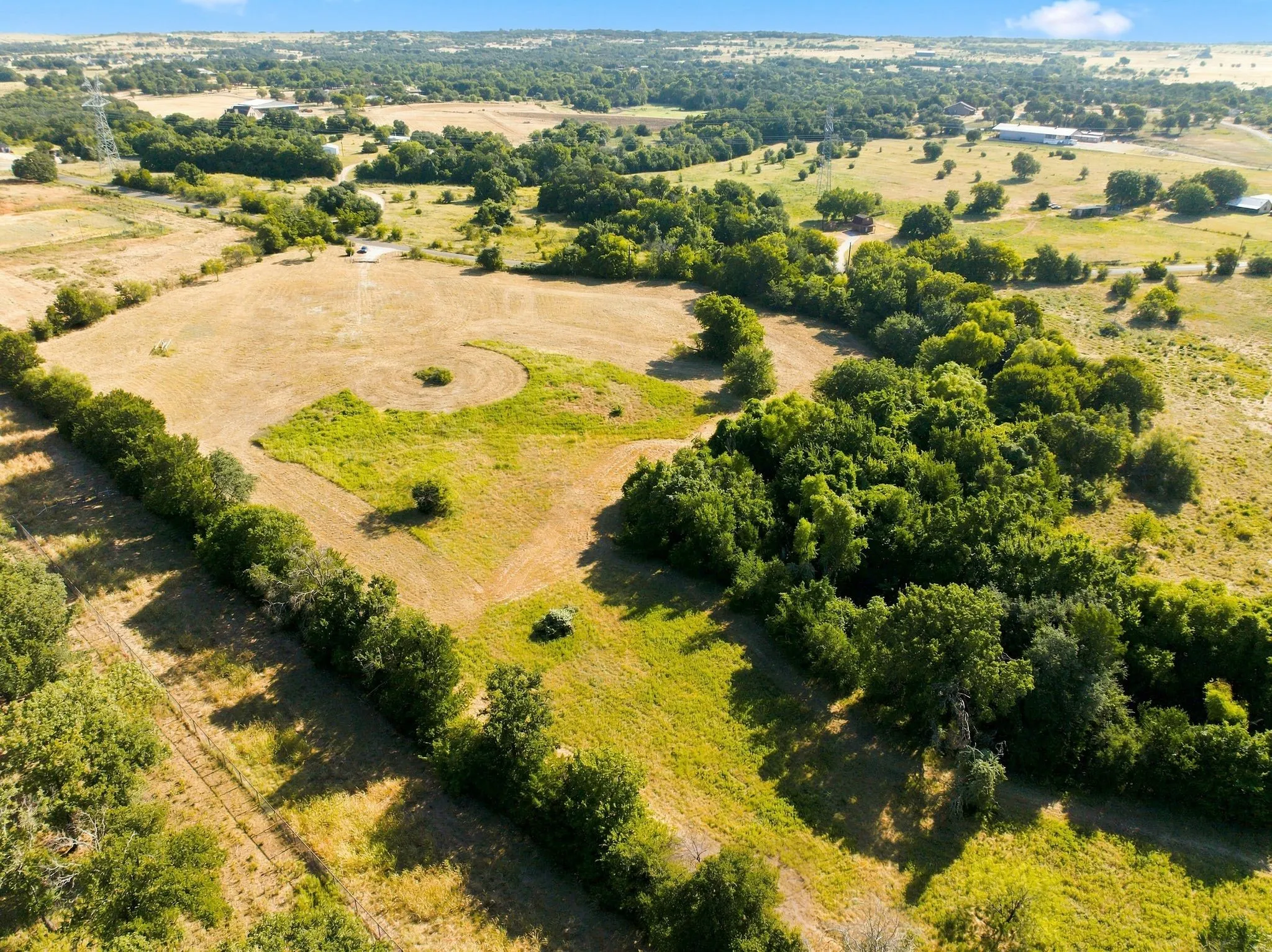 Expansive rural acreage featuring gently rolling pastureland with mature tree clusters throughout