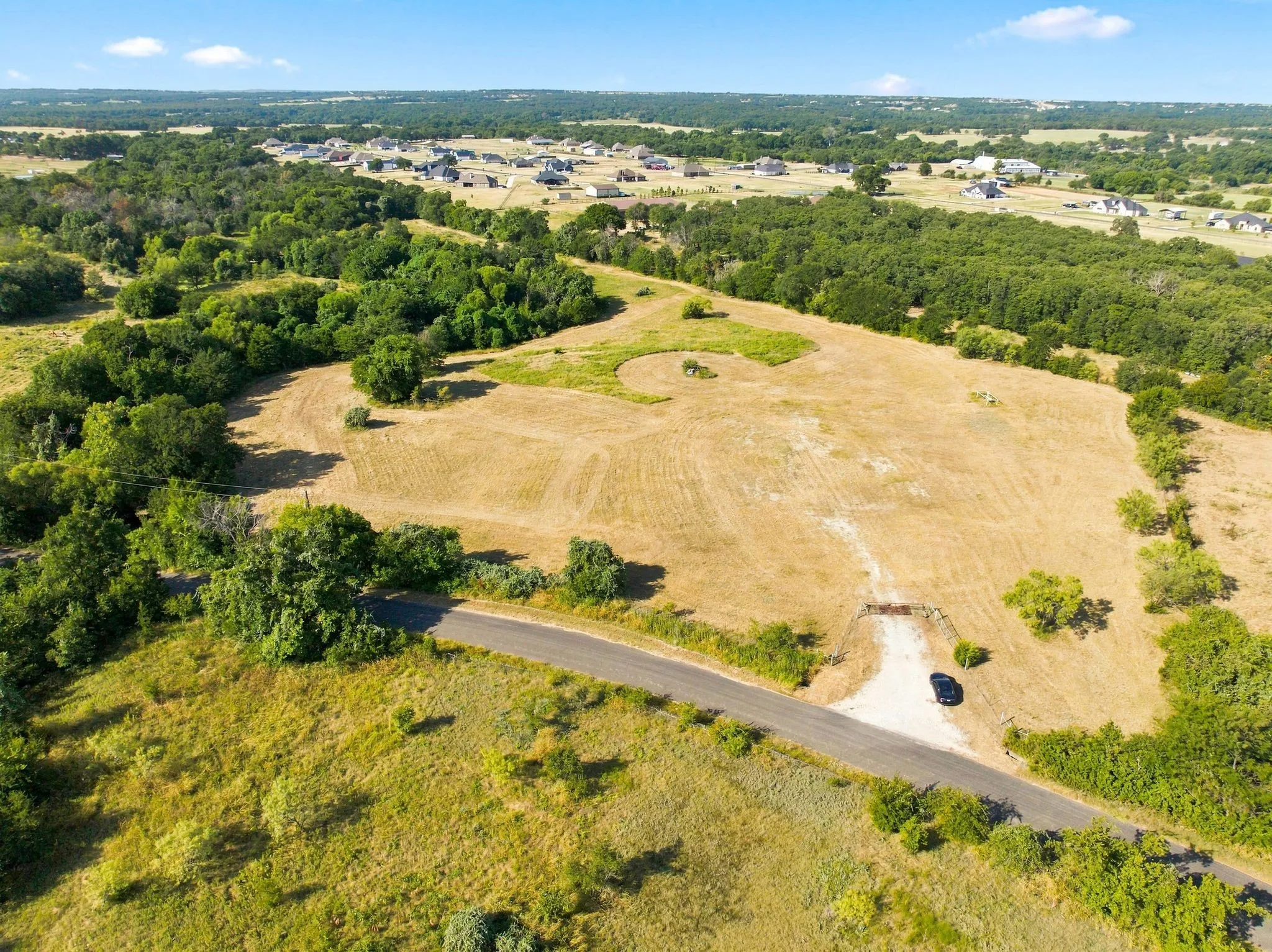 Expansive rural acreage featuring gently rolling pastureland with mature tree clusters and natural landscaping