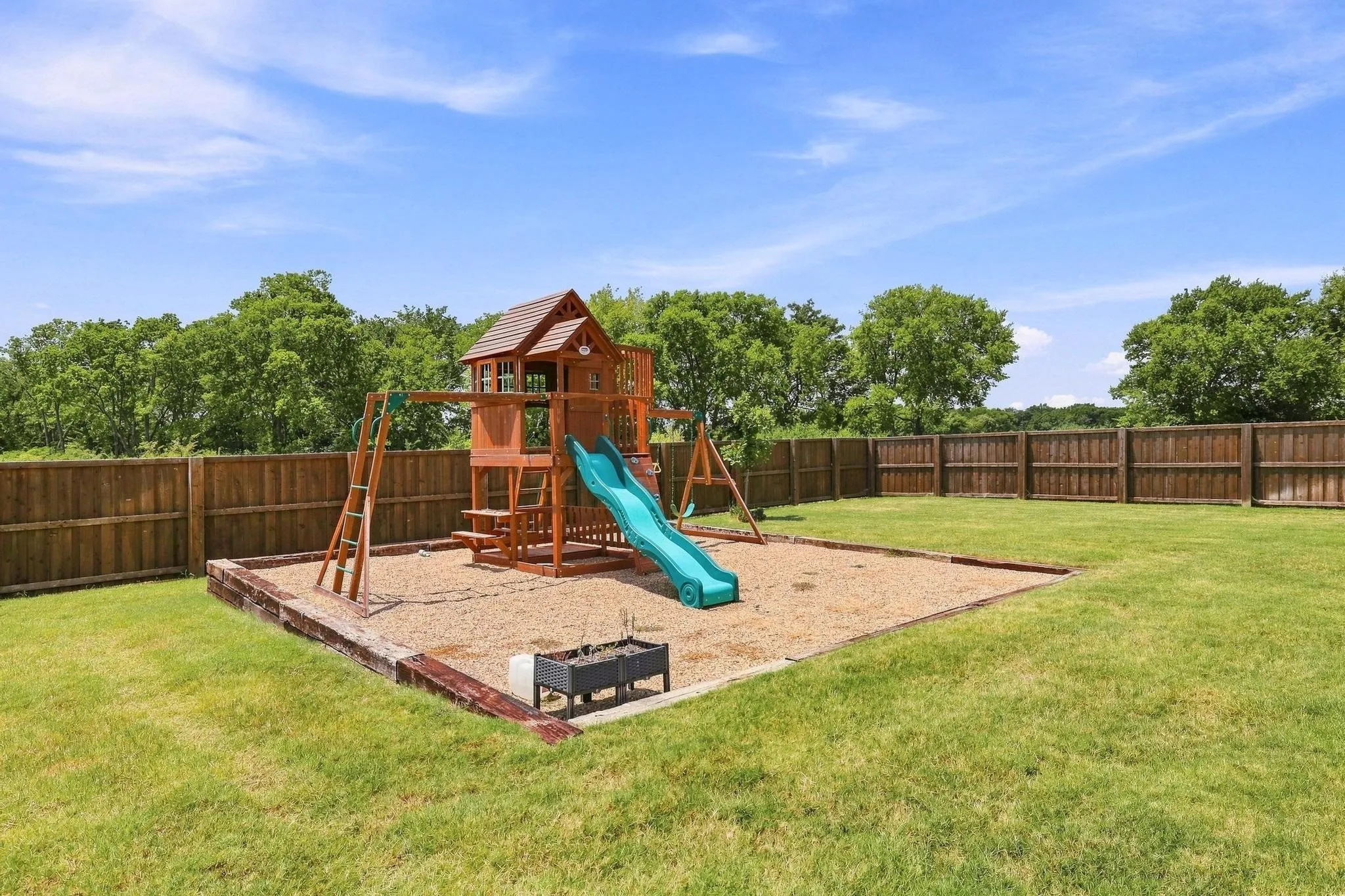Expansive fenced backyard featuring a grassy lawn and a built-in play structure