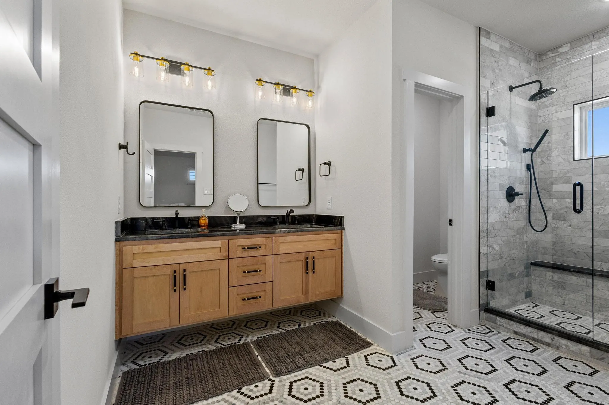 Bathroom featuring a dual vanity with wood-finish cabinetry and a dark stone countertop