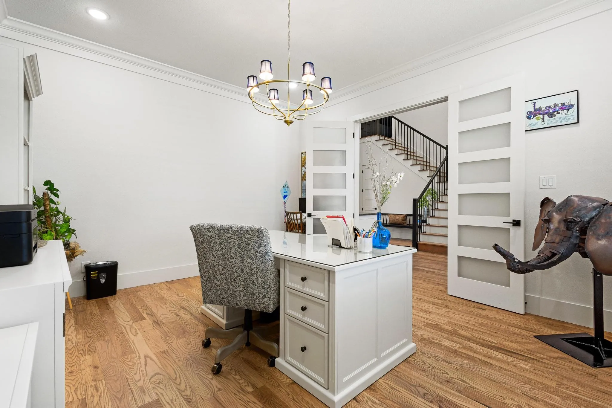 Hardwood flooring throughout, featuring a modern chandelier, crown molding, and recessed lighting
