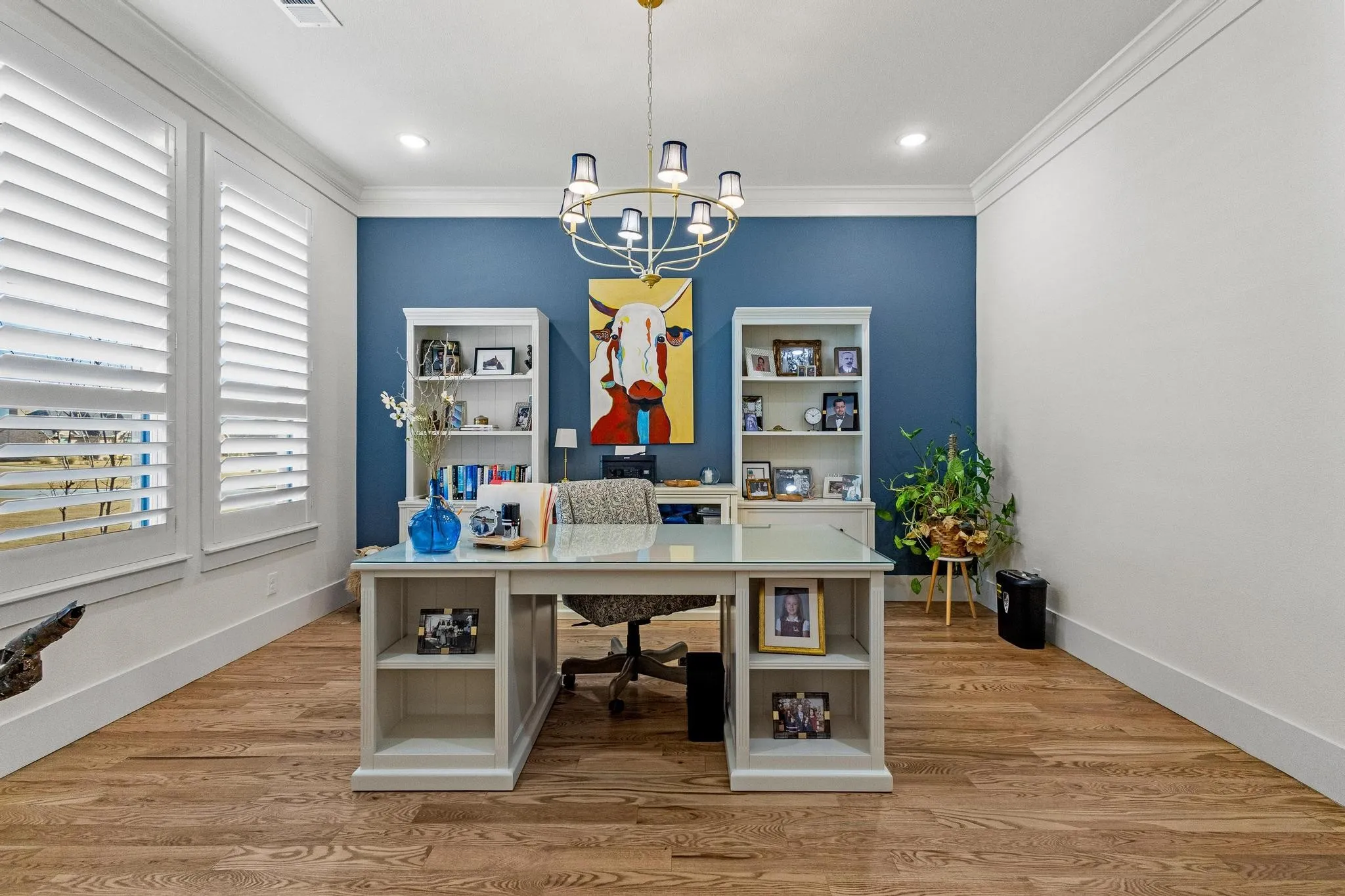 Bright interior space featuring wood-finish flooring, white plantation shutters, and crown molding