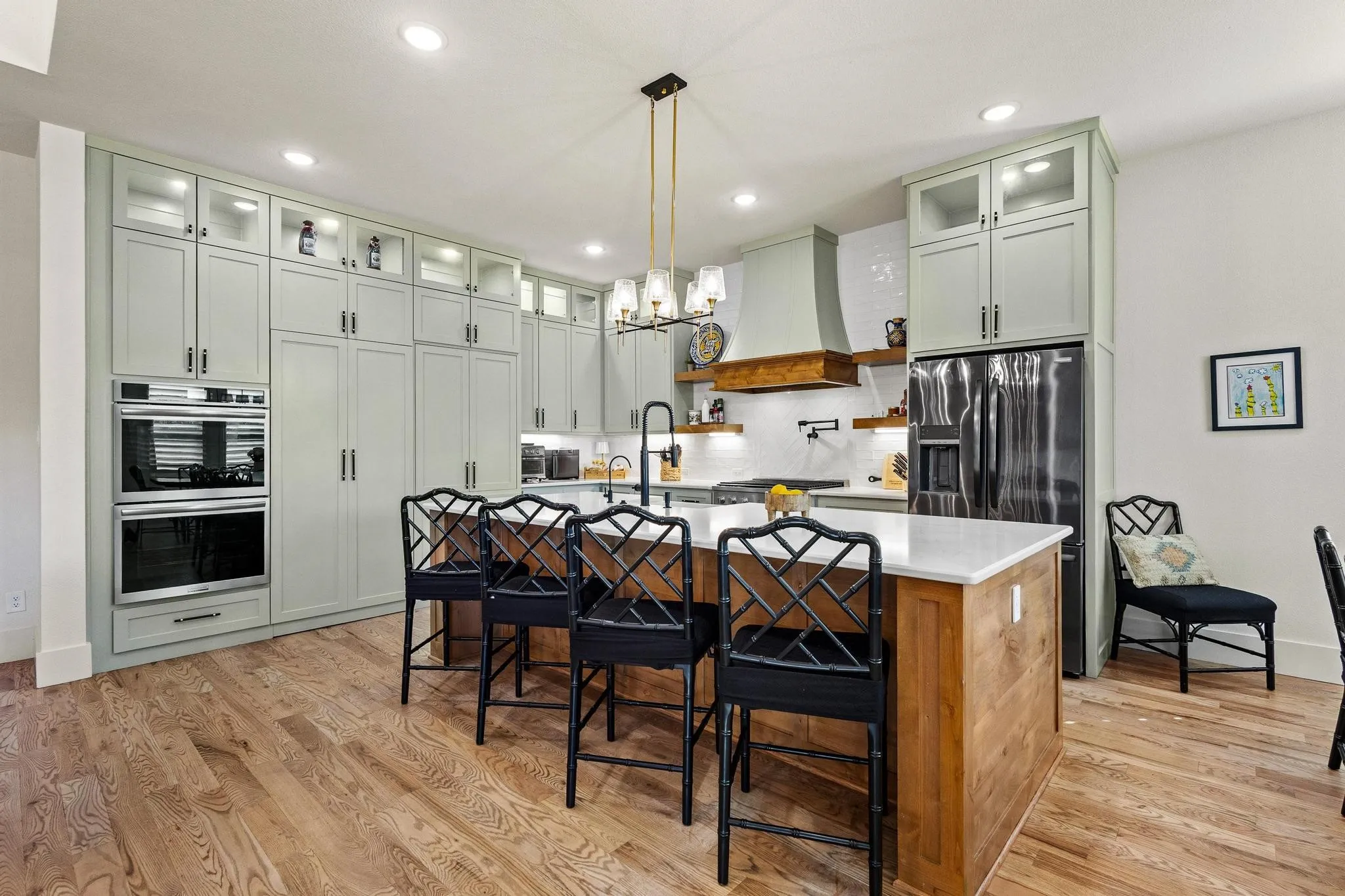 Kitchen featuring an expansive island with a light-toned countertop and wood-finish paneling, complemented by hardwood flooring