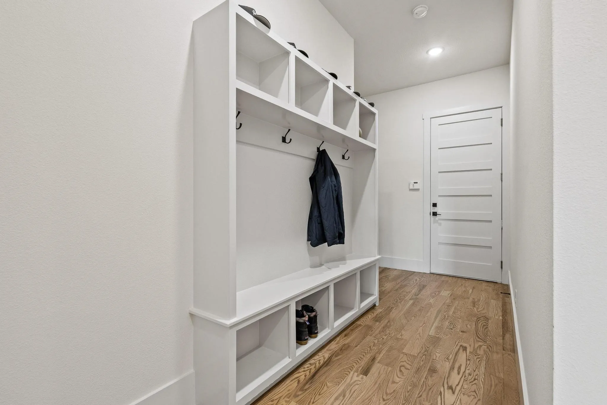 Built-in white storage unit featuring shelving and coat hooks