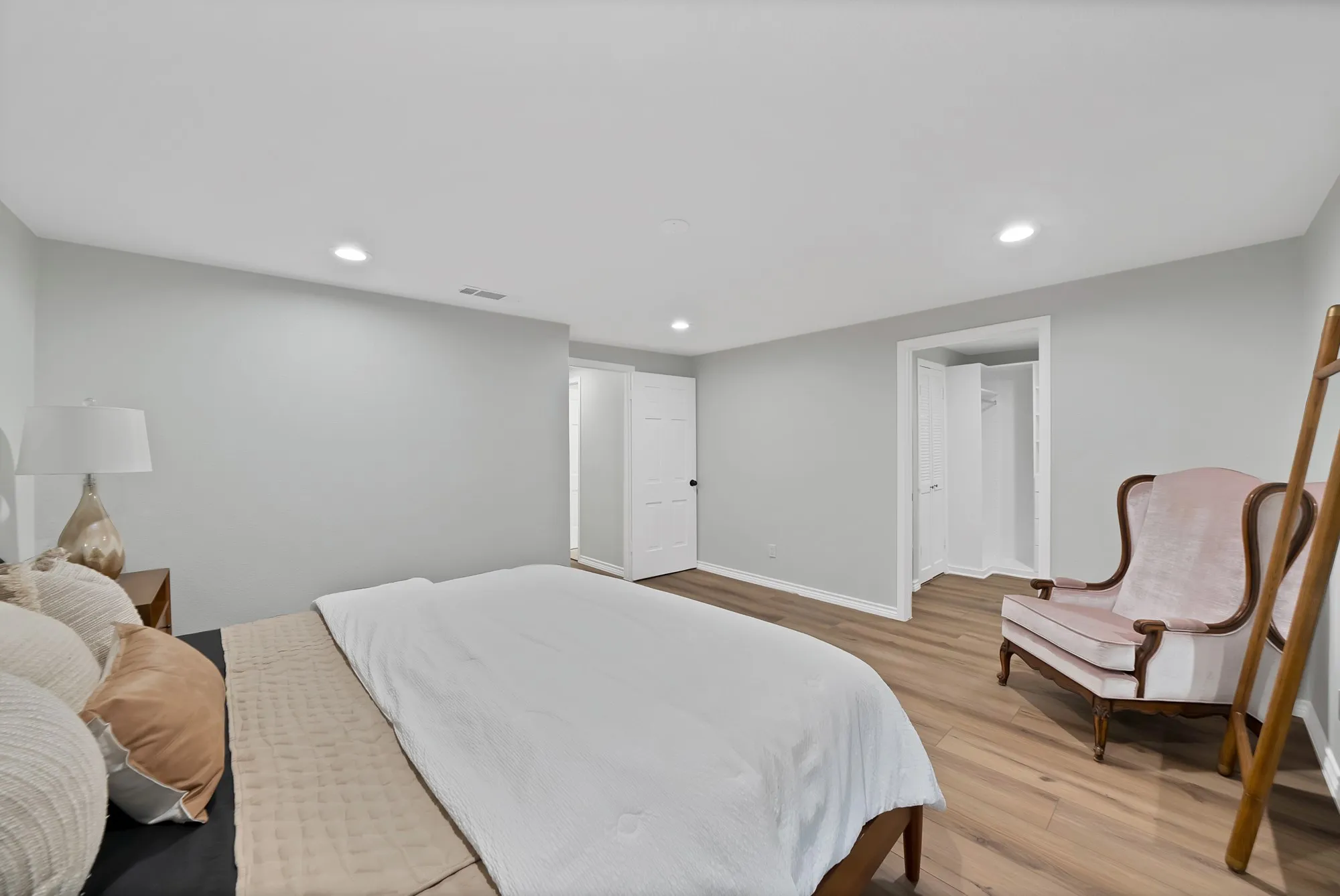 Recessed ceiling lighting, wood-finish flooring, white walls, white trim, and a bi-fold closet door