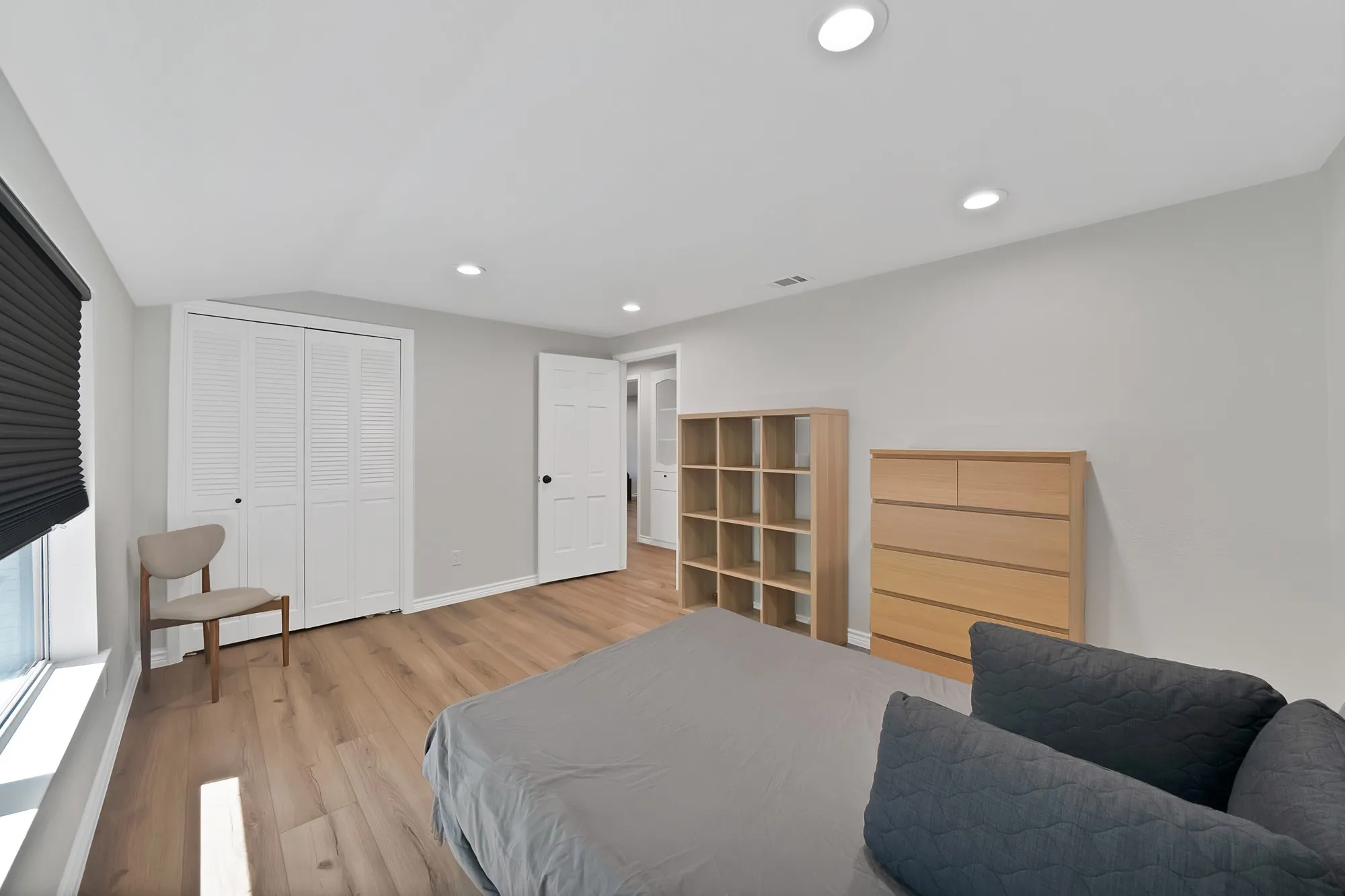 Wood-finish flooring, recessed lighting, and a window with black privacy blinds