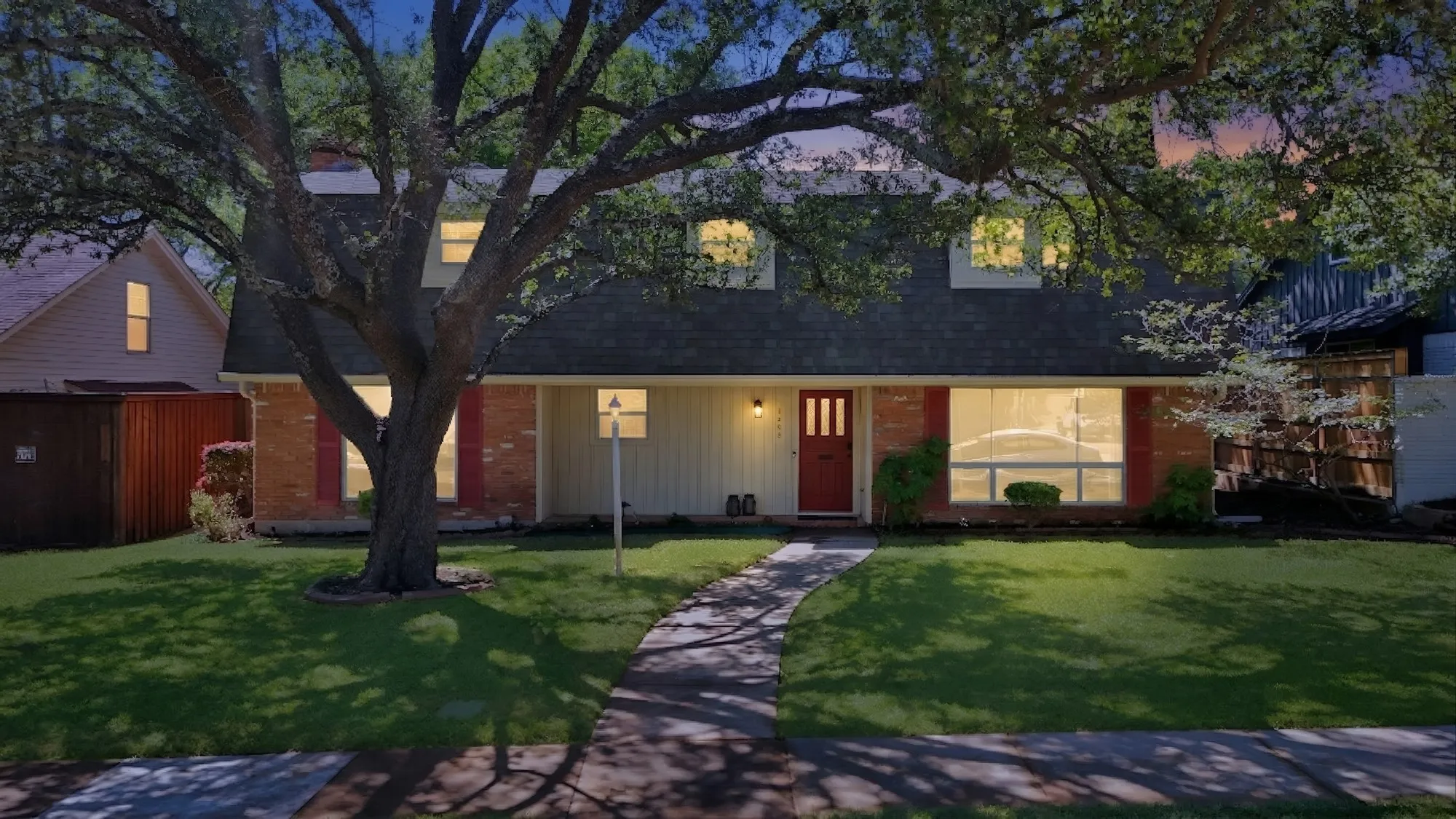 Traditional-style exterior with a red front door, brick accents, and a front lawn with a mature tree