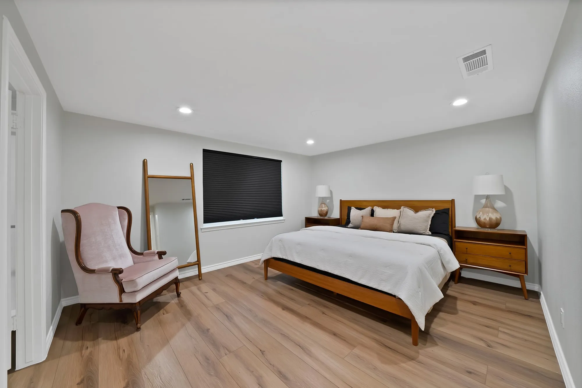 Recessed lighting, light gray wall finish, wood-finish flooring, and a window with dark blinds