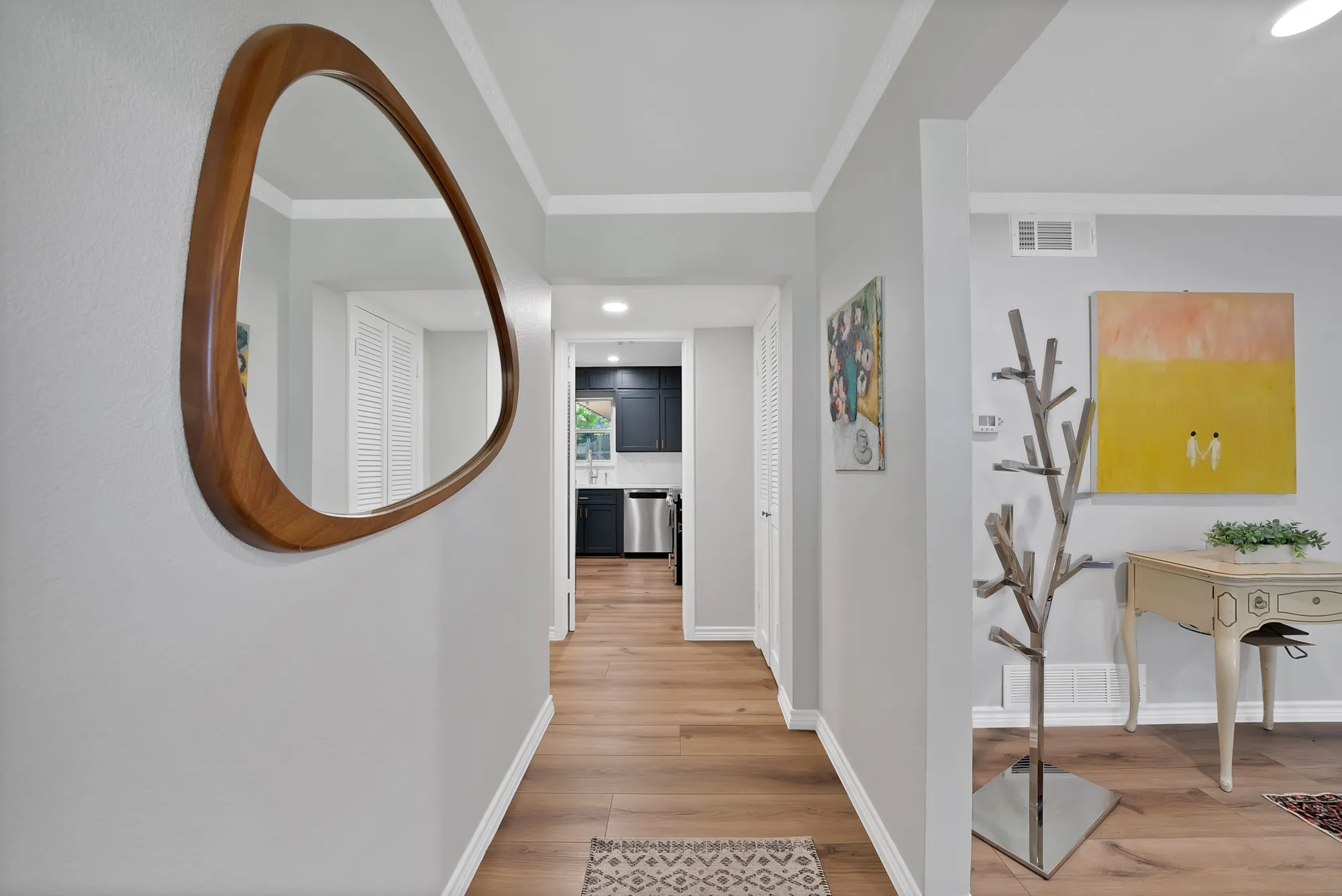 Wood-finish flooring throughout, white baseboards, and crown molding