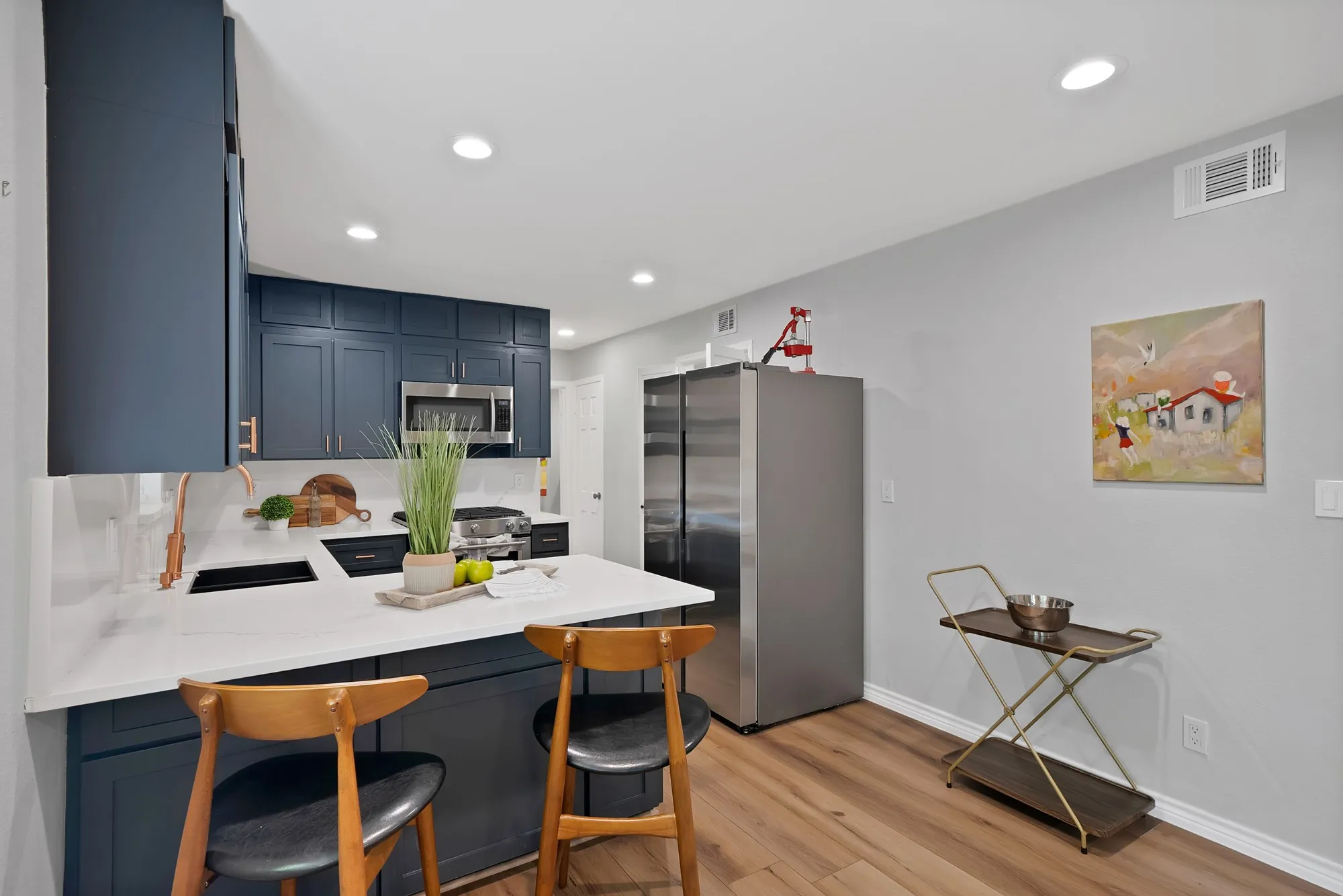 Kitchen featuring white countertops, navy cabinetry, stainless steel appliances, wood-finish flooring, and recessed lighting