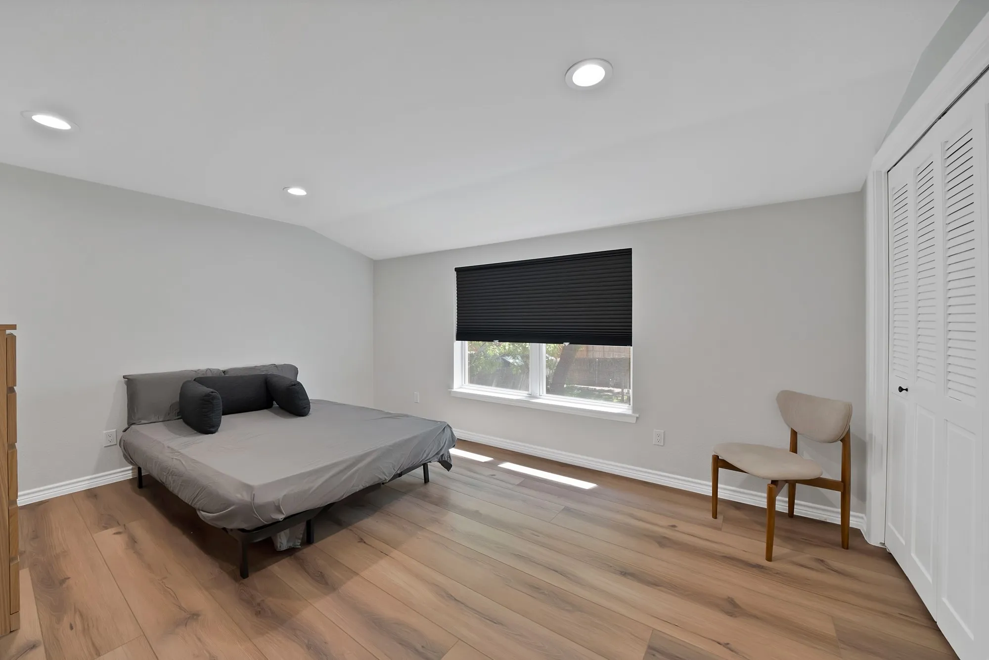 Recessed ceiling lighting, wood-finish flooring, white baseboards, and a window with a cellular shade