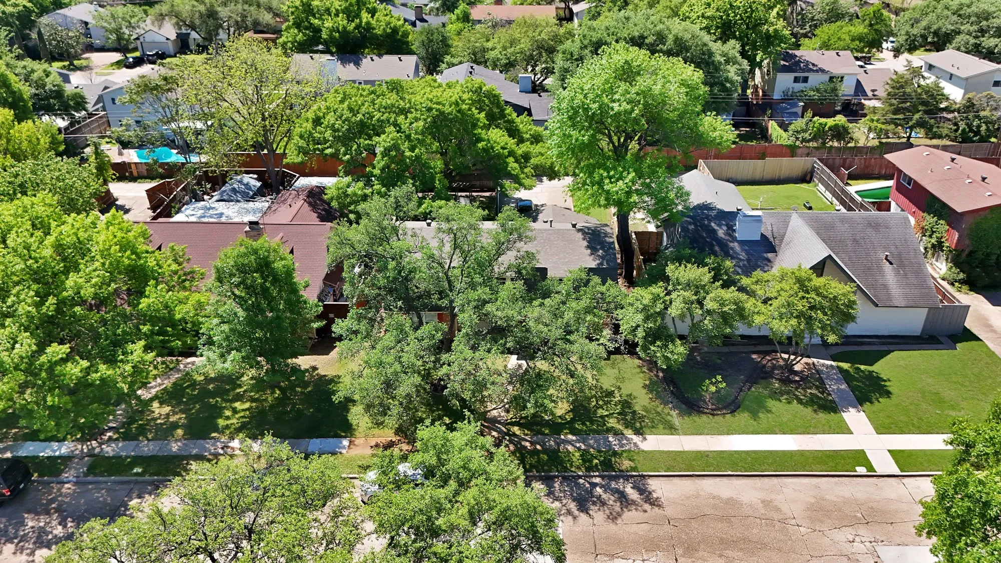 Expansive backyard featuring a brick patio, mature trees, and a privacy fence
