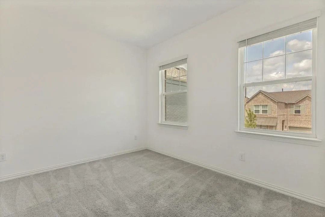 White walls, two windows with blinds, and light gray carpet