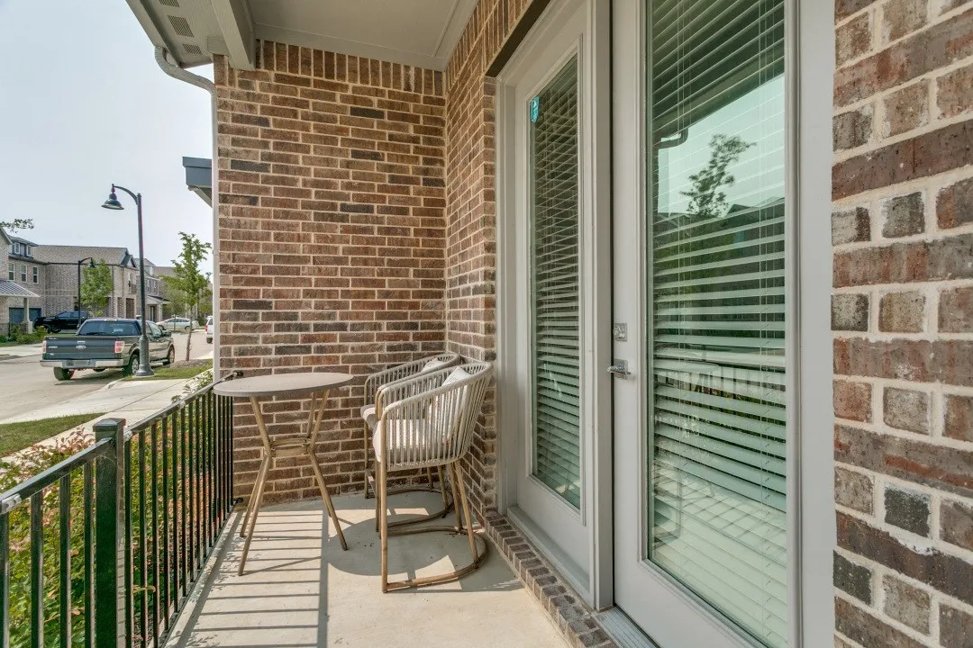 Private balcony featuring brick exterior, metal railing, and light-colored flooring
