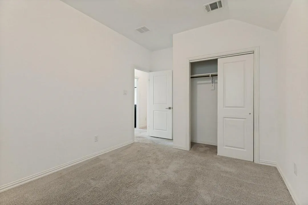 Neutral-toned carpeting, white walls, and a sliding two-panel closet door