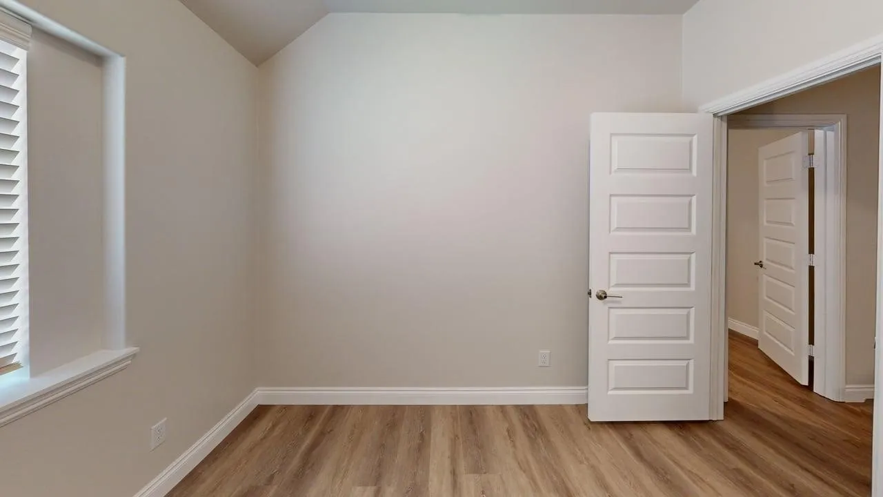 Wood-finish flooring, neutral wall tones, white trim, window with blinds, and paneled interior doors