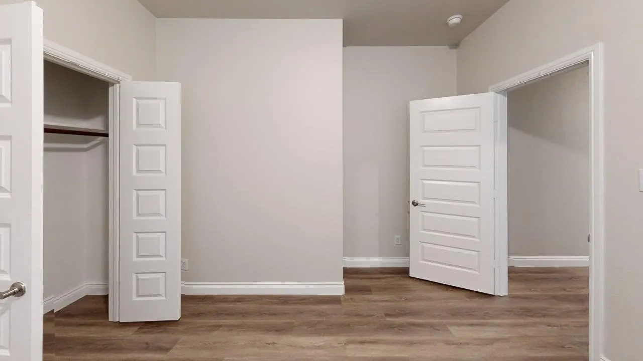 Wood-finish flooring, white paneled doors, and a built-in closet with a hanging rod
