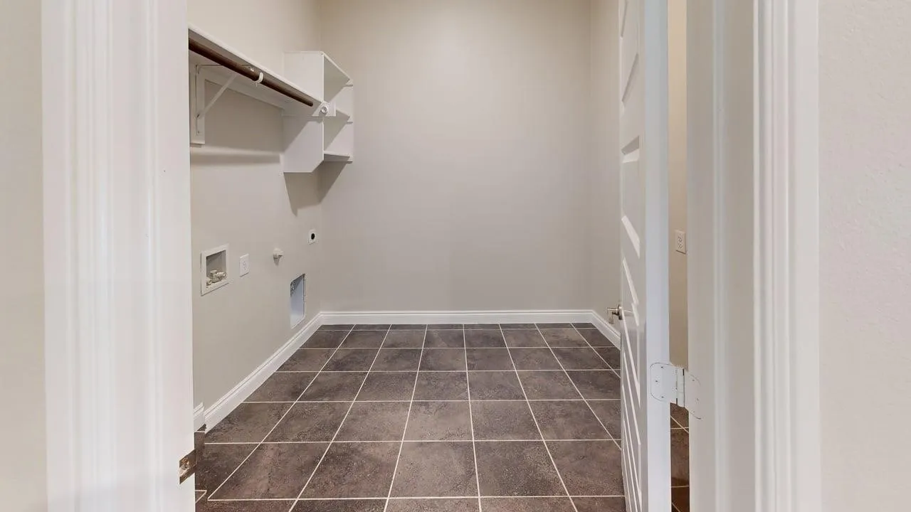 Spacious utility room featuring tile flooring, built-in shelving, and a hanging rod