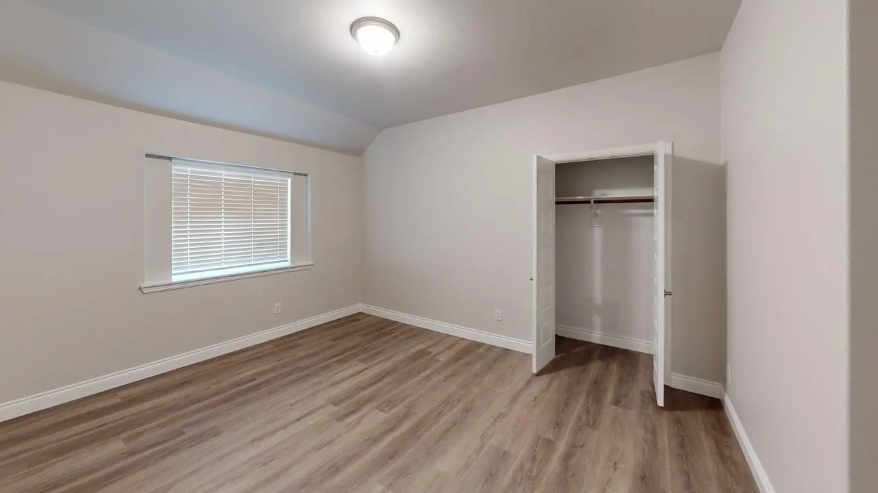 Wood-finish flooring, recessed ceiling lighting, window with horizontal blinds, and a built-in closet with double doors and a hanging rod