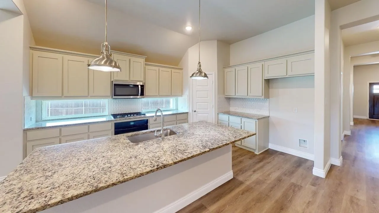 Kitchen featuring an island with stone countertops, stainless steel appliances, light-toned cabinetry, and wood-finish flooring