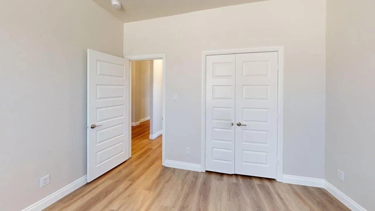 Wood-finish flooring, white paneled doors, high ceilings, and neutral wall tones