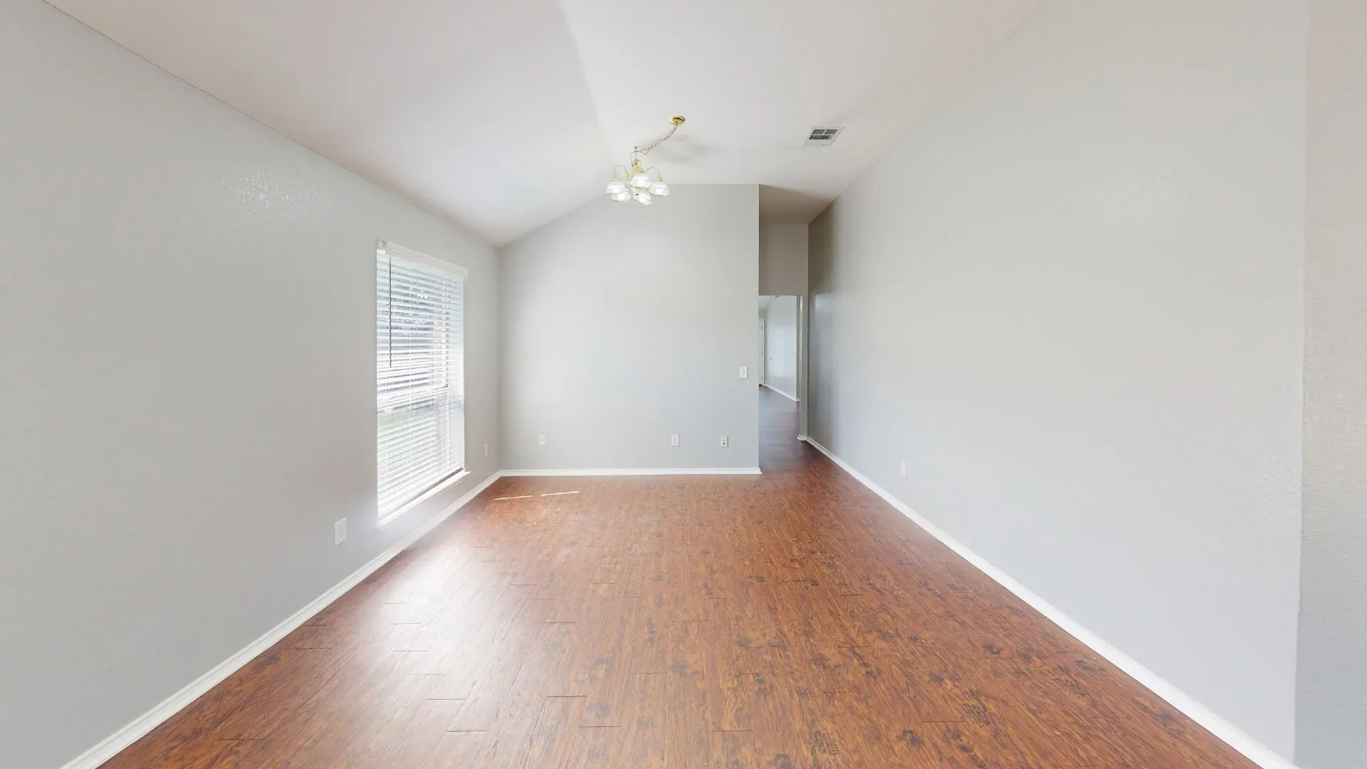 Bright, light-filled hallway showcasing warm wood-finish flooring, clean white walls, and recessed ceiling lighting