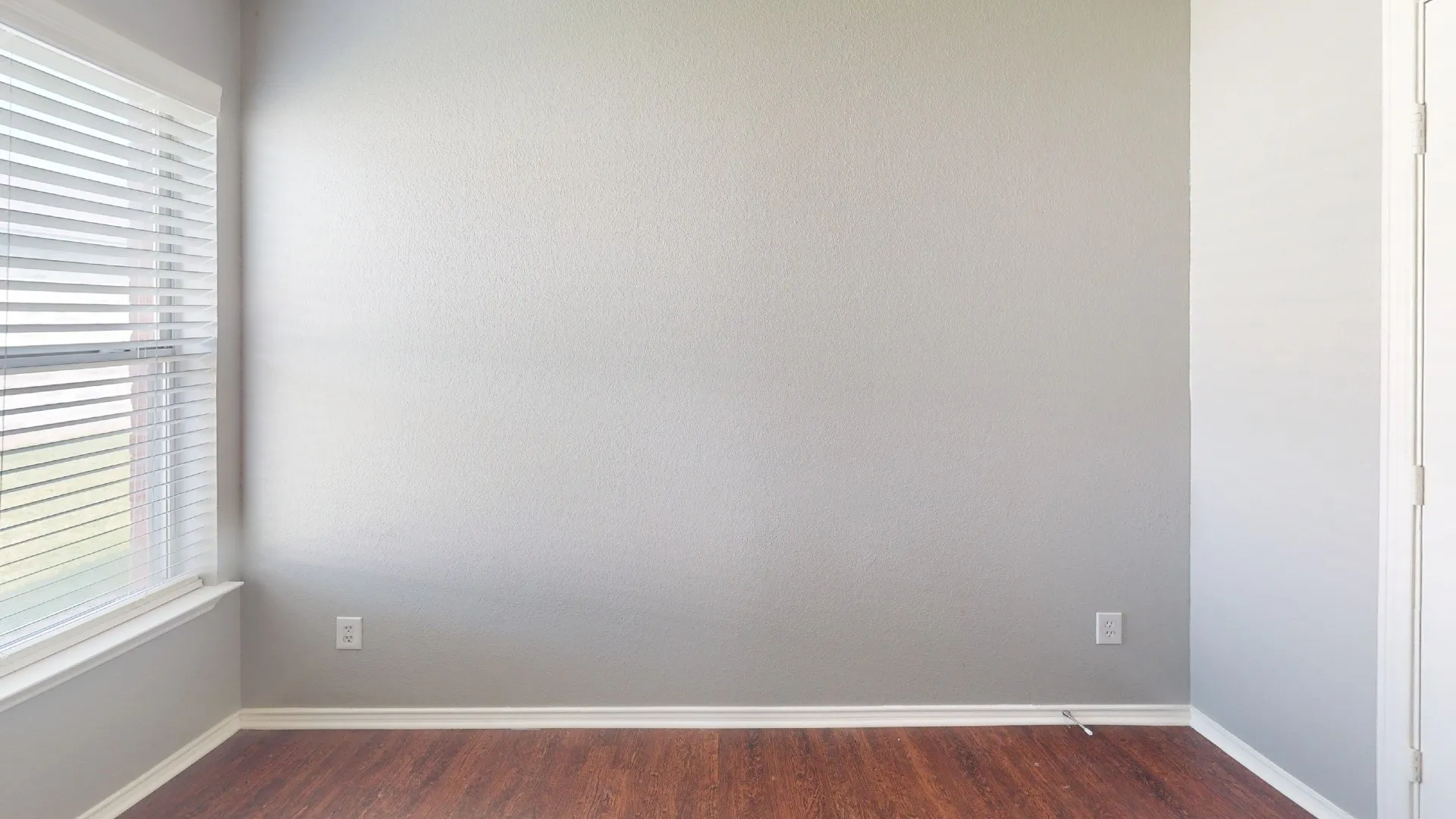 Wood-finish flooring, light gray wall paint, and white baseboards
