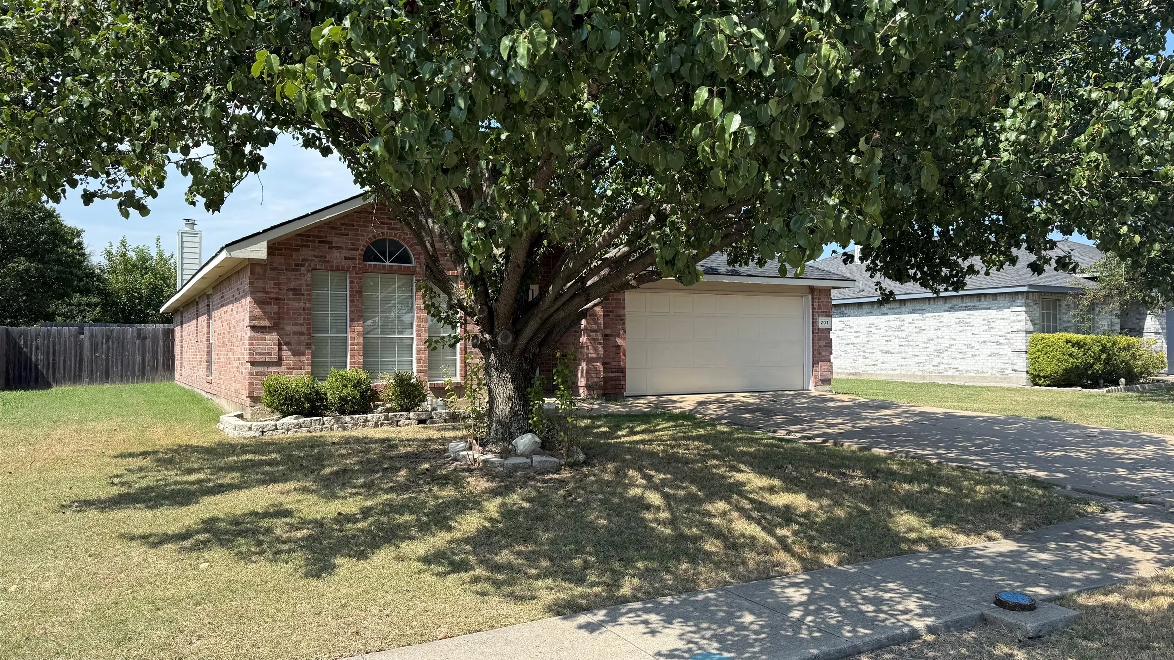 Brick exterior with a gabled roof, arched window, and attached garage