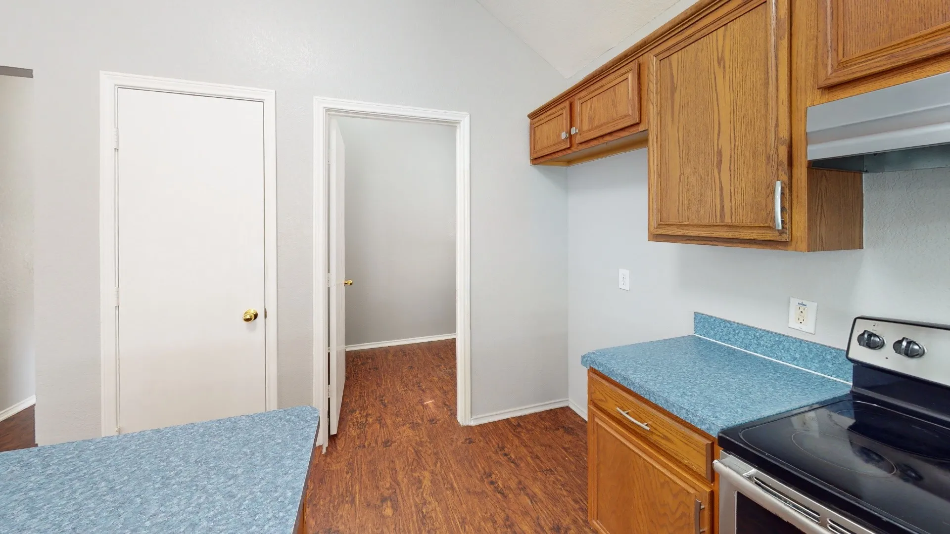 Kitchen featuring wood-finish flooring, wood cabinetry, blue speckled countertops, and a built-in stainless steel range